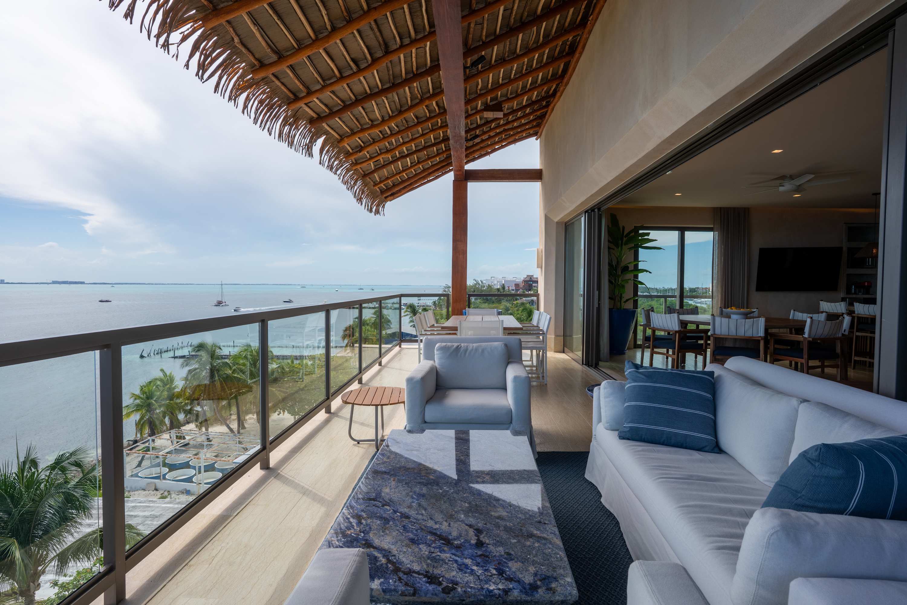 Ocean view balcony with seating and thatched roof.