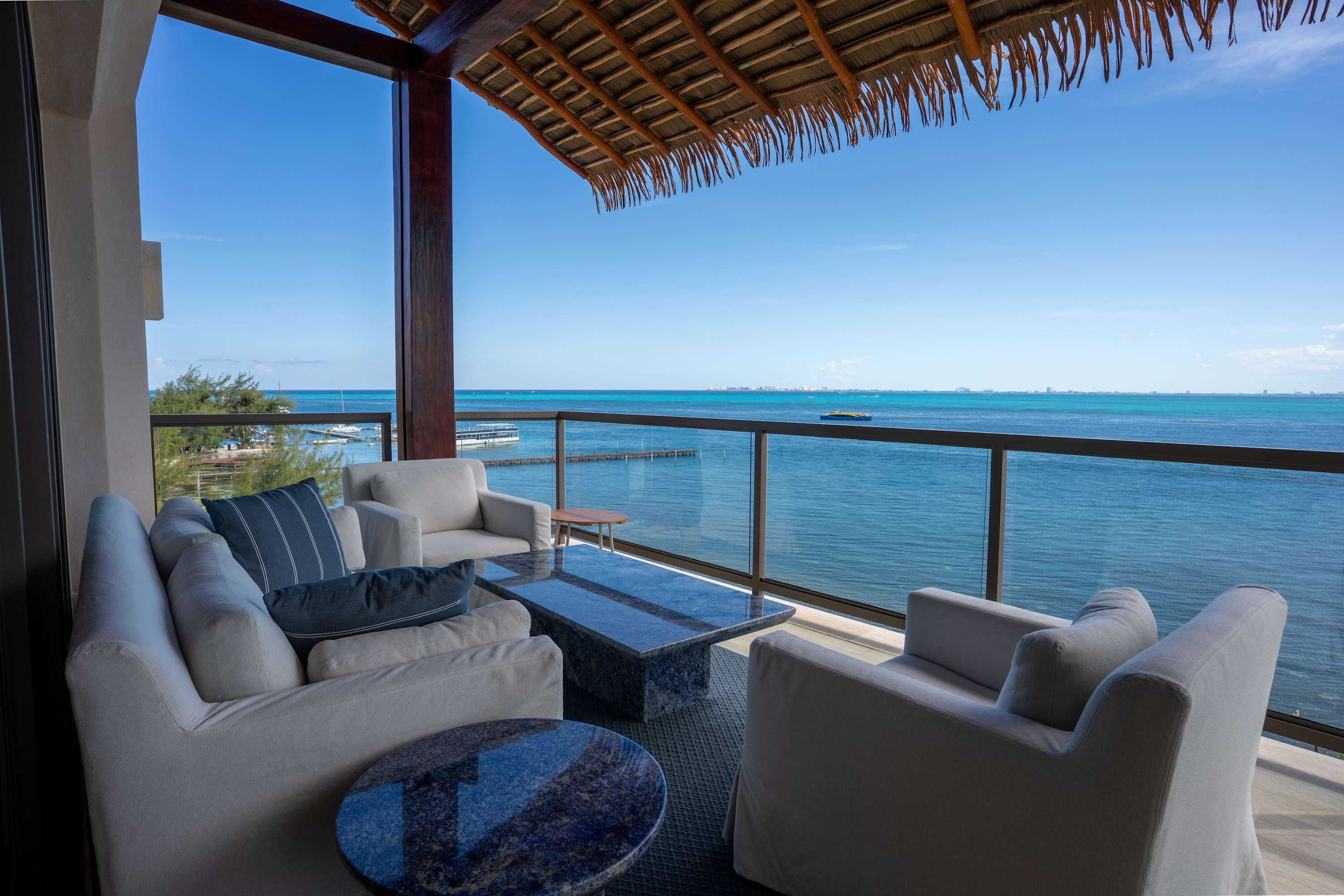 A covered balcony with comfortable seating overlooks the ocean.