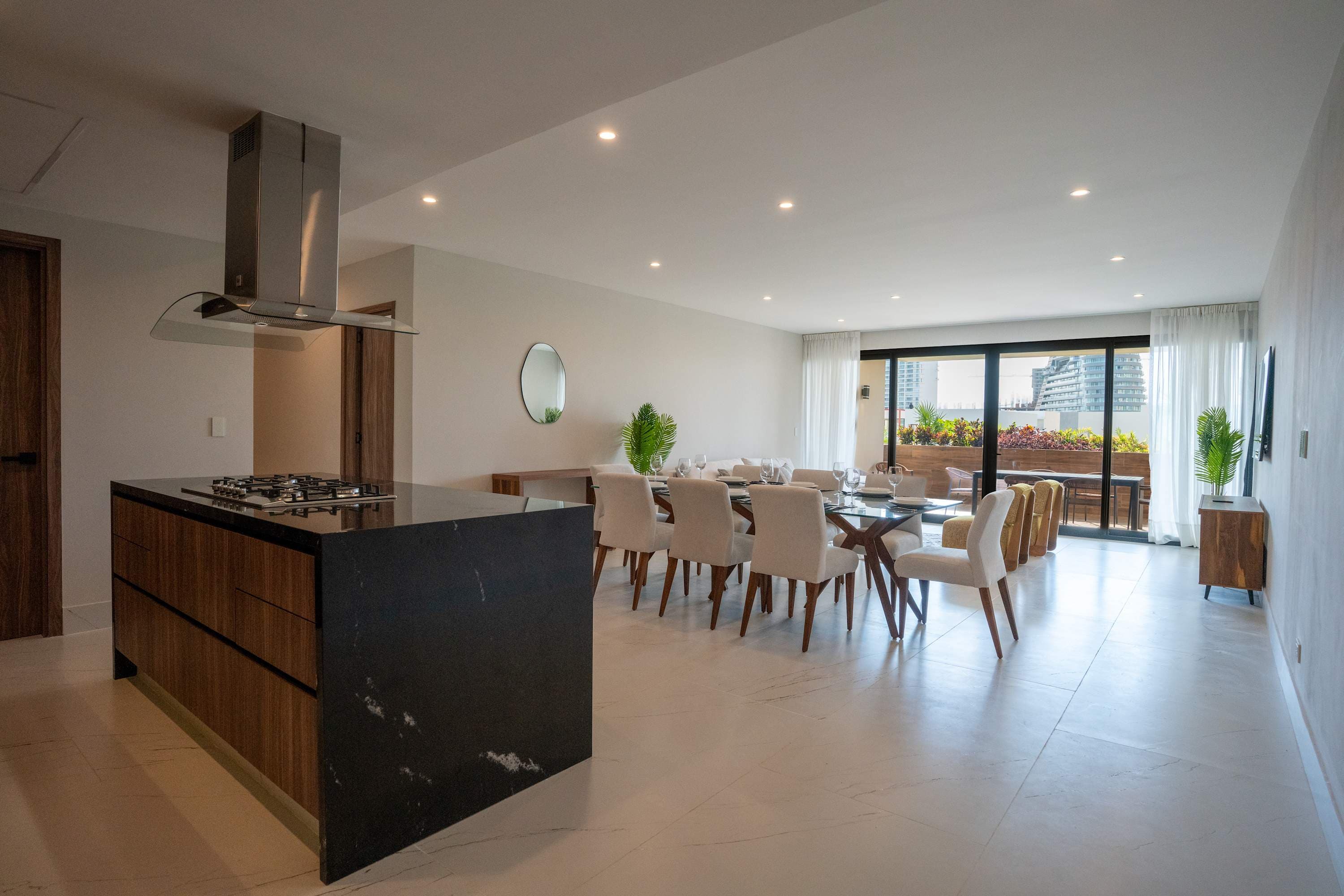 Modern open-plan kitchen, dining, and living area with island, dining table, and patio access.