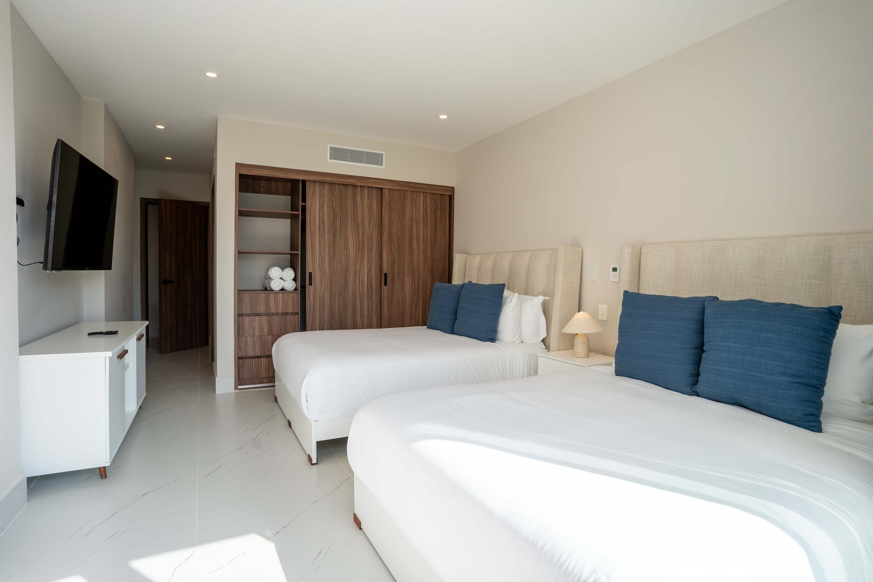 A bedroom with two beds, a TV, and a closet.