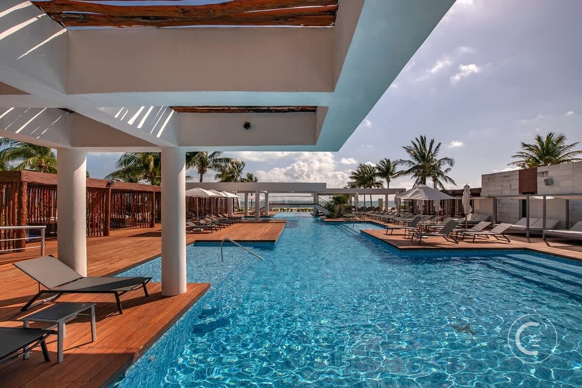 An inviting resort pool with lounge chairs and umbrellas, surrounded by palm trees.