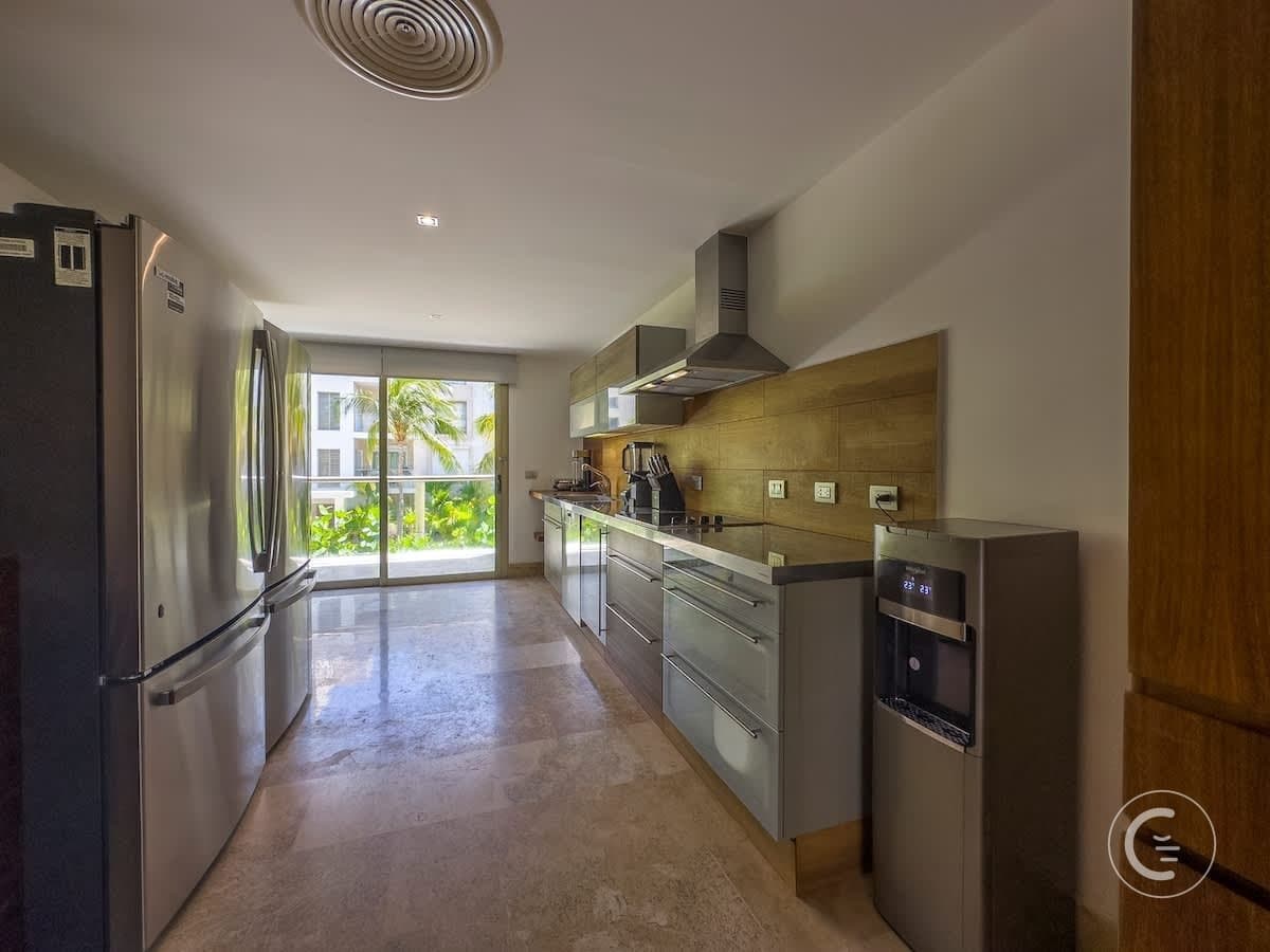 A modern kitchen with stainless steel appliances, including a refrigerator and a water dispenser.