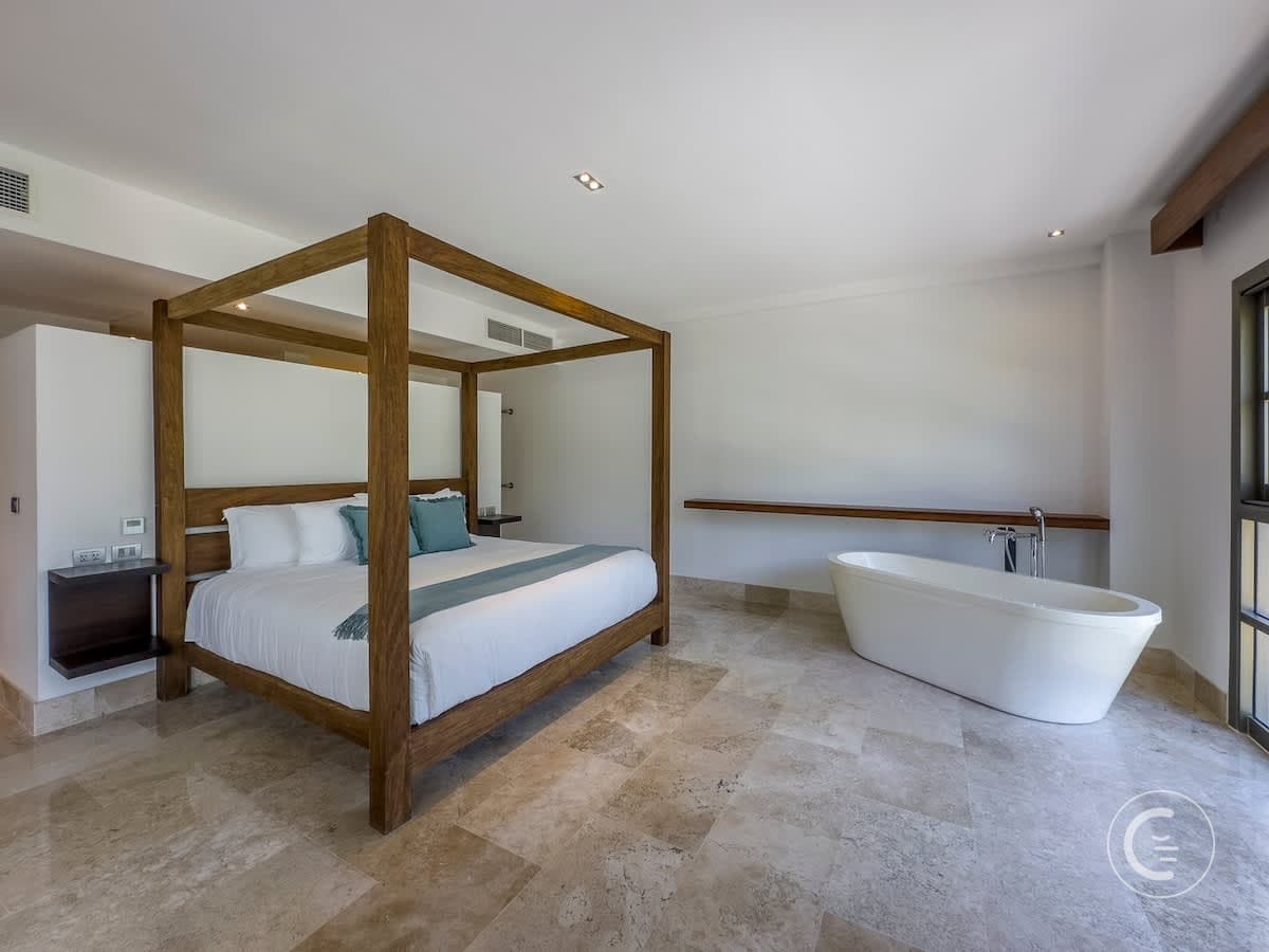 A spacious bedroom with a four-poster bed and a freestanding bathtub.