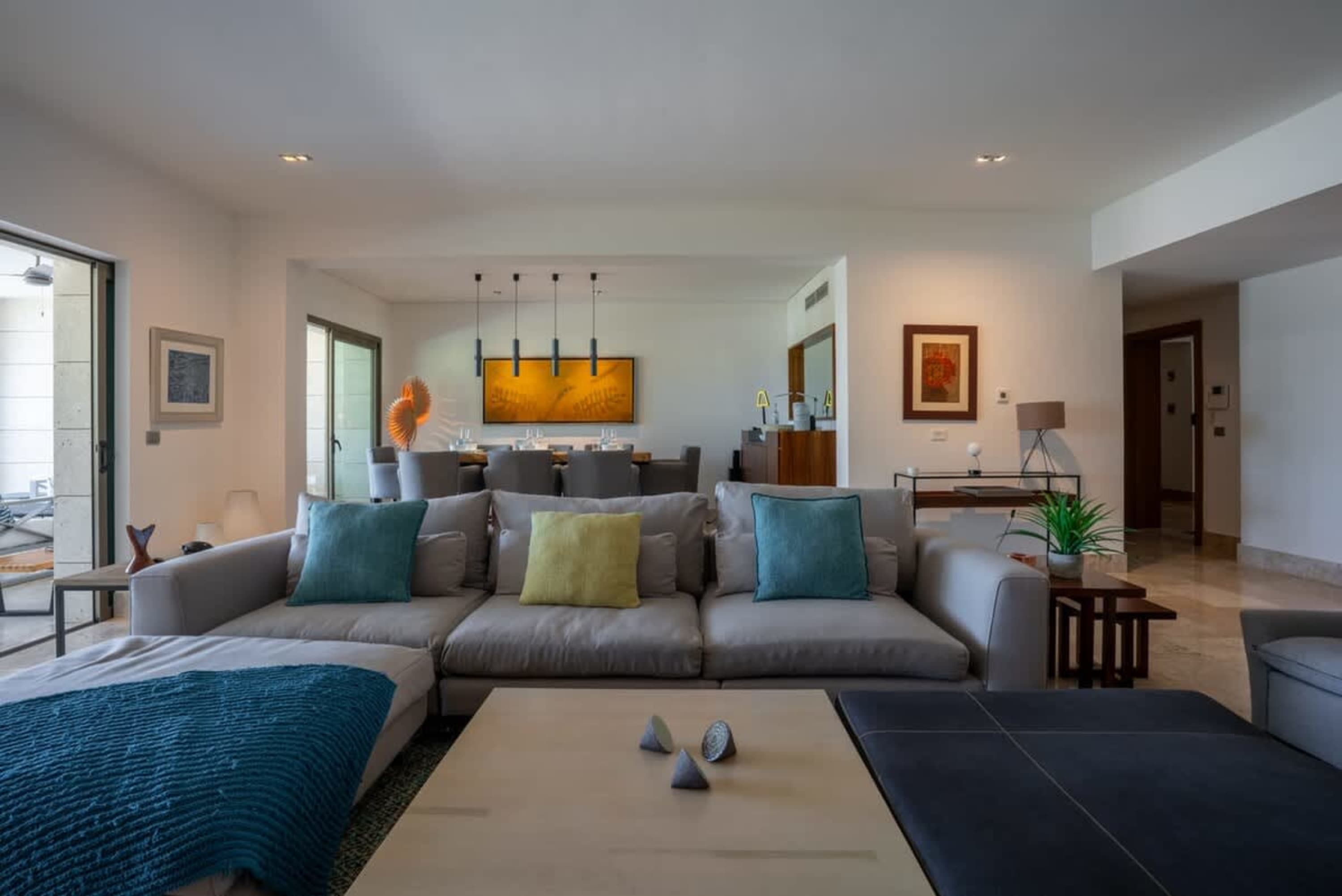 Modern living room with a large sectional sofa, coffee table, and dining area in the background.