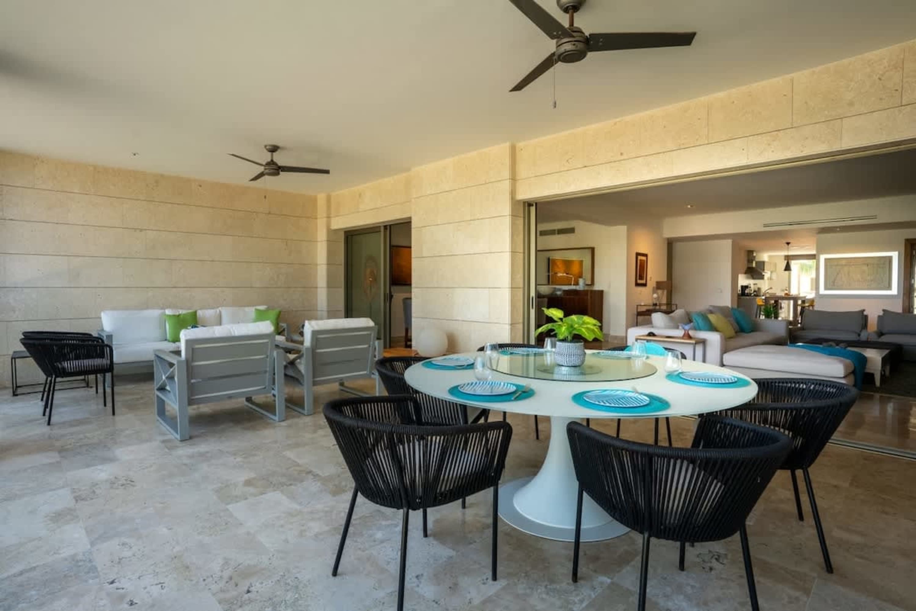 Outdoor patio with dining table, chairs, and sofas leading into a living room.