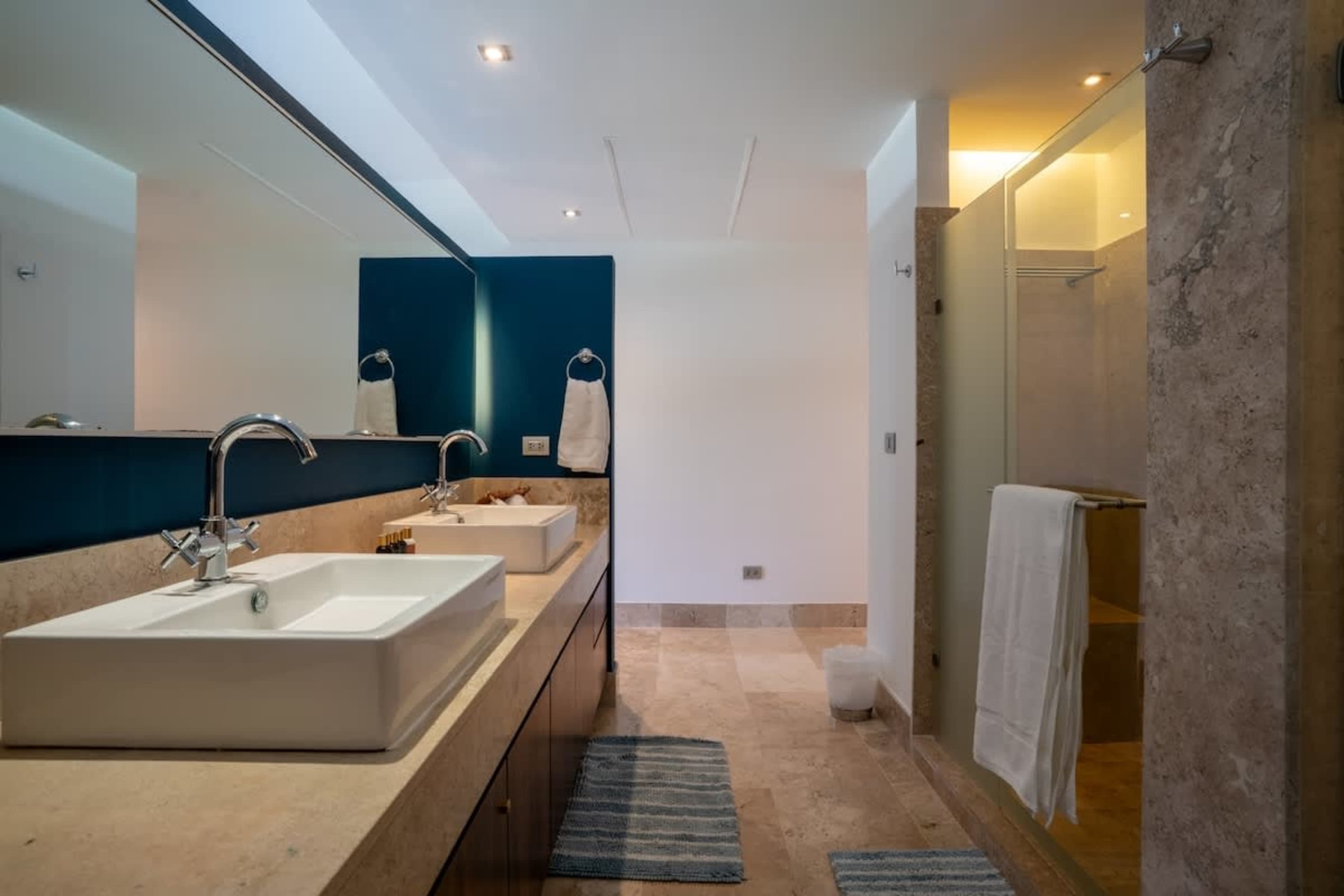 Modern bathroom with double sinks, a shower, and marble accents.