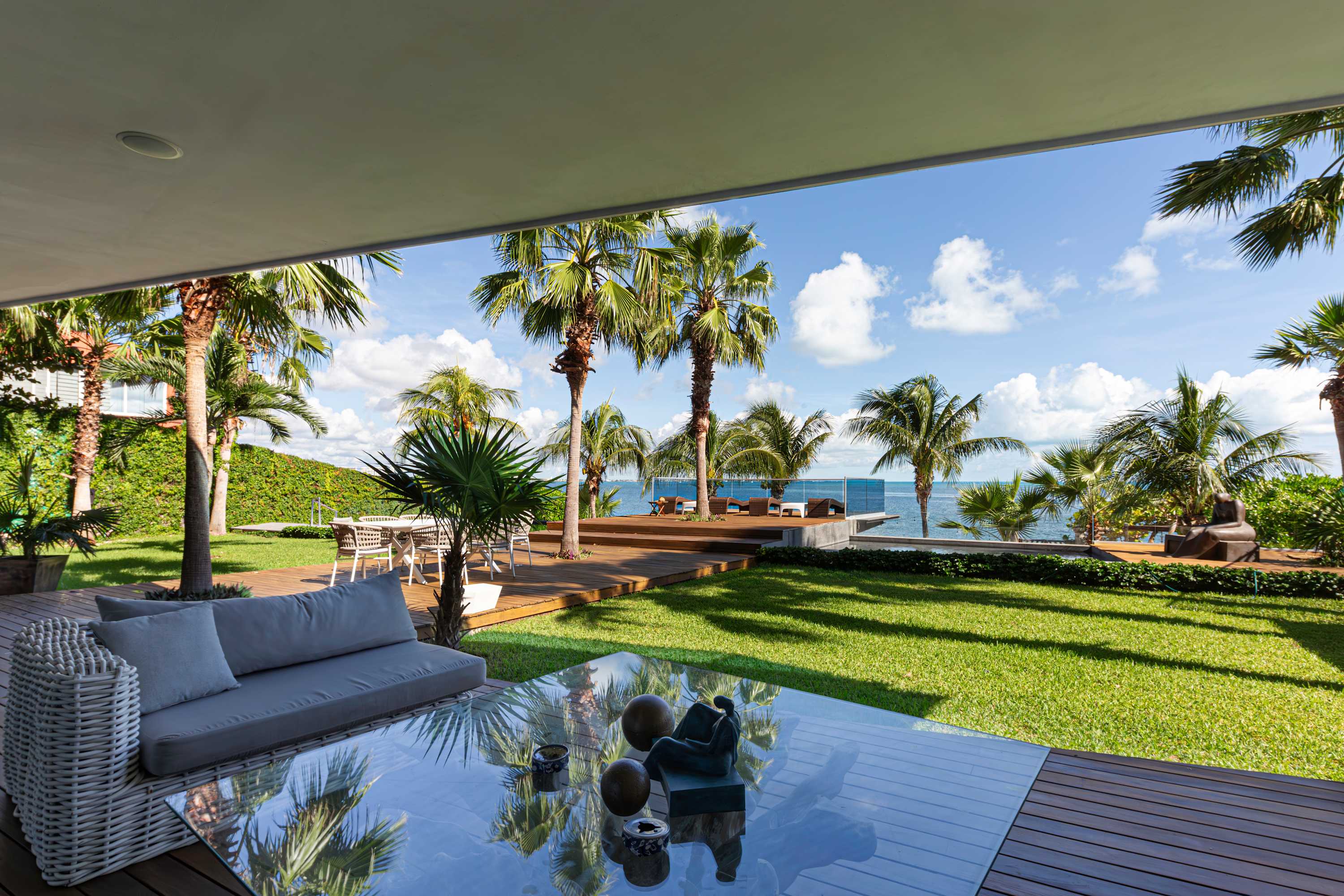Outdoor living room with a sofa, coffee table, and palm trees.