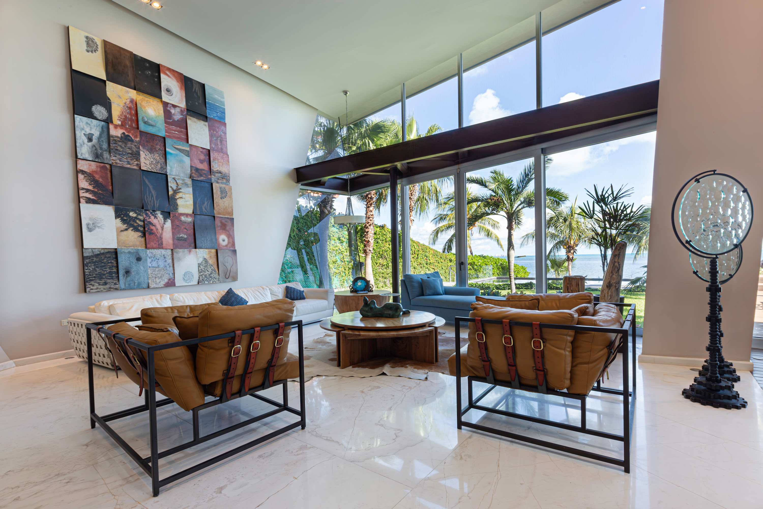 A modern living room with large windows overlooking a tropical landscape.