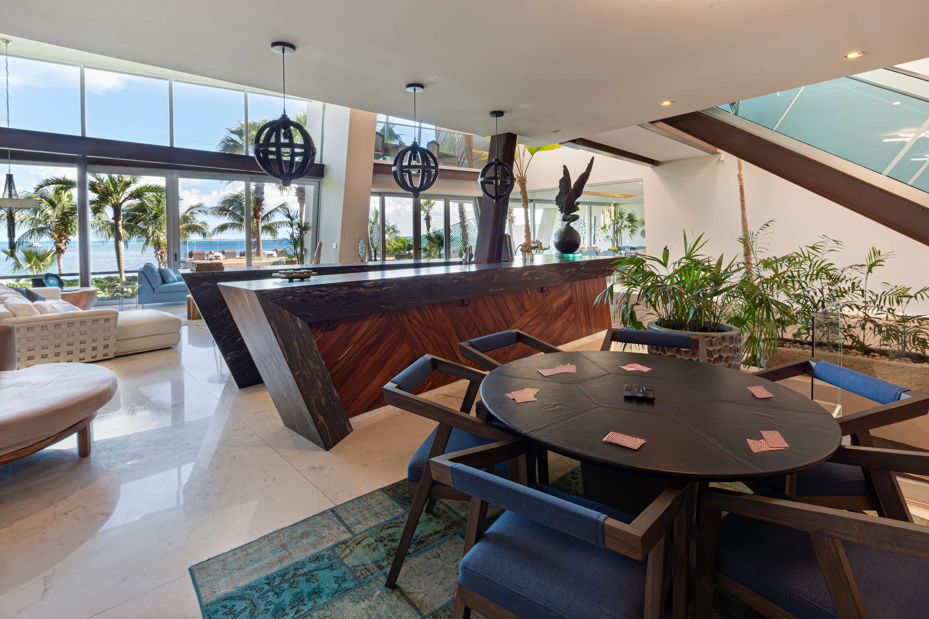 A modern living room with a bar, dining table, and ocean view.
