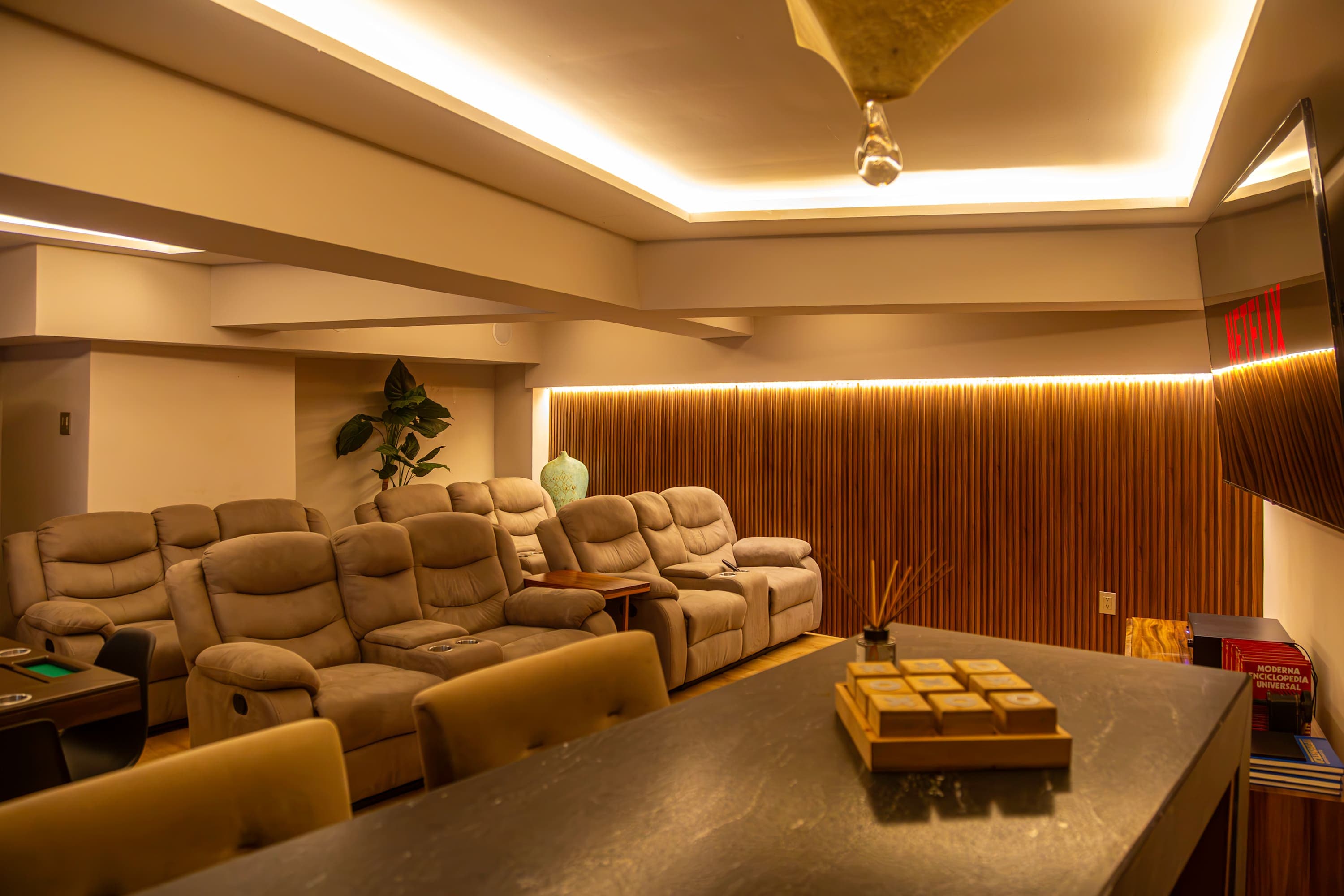Home theater with plush reclining chairs, a large TV, and wood-paneled walls.