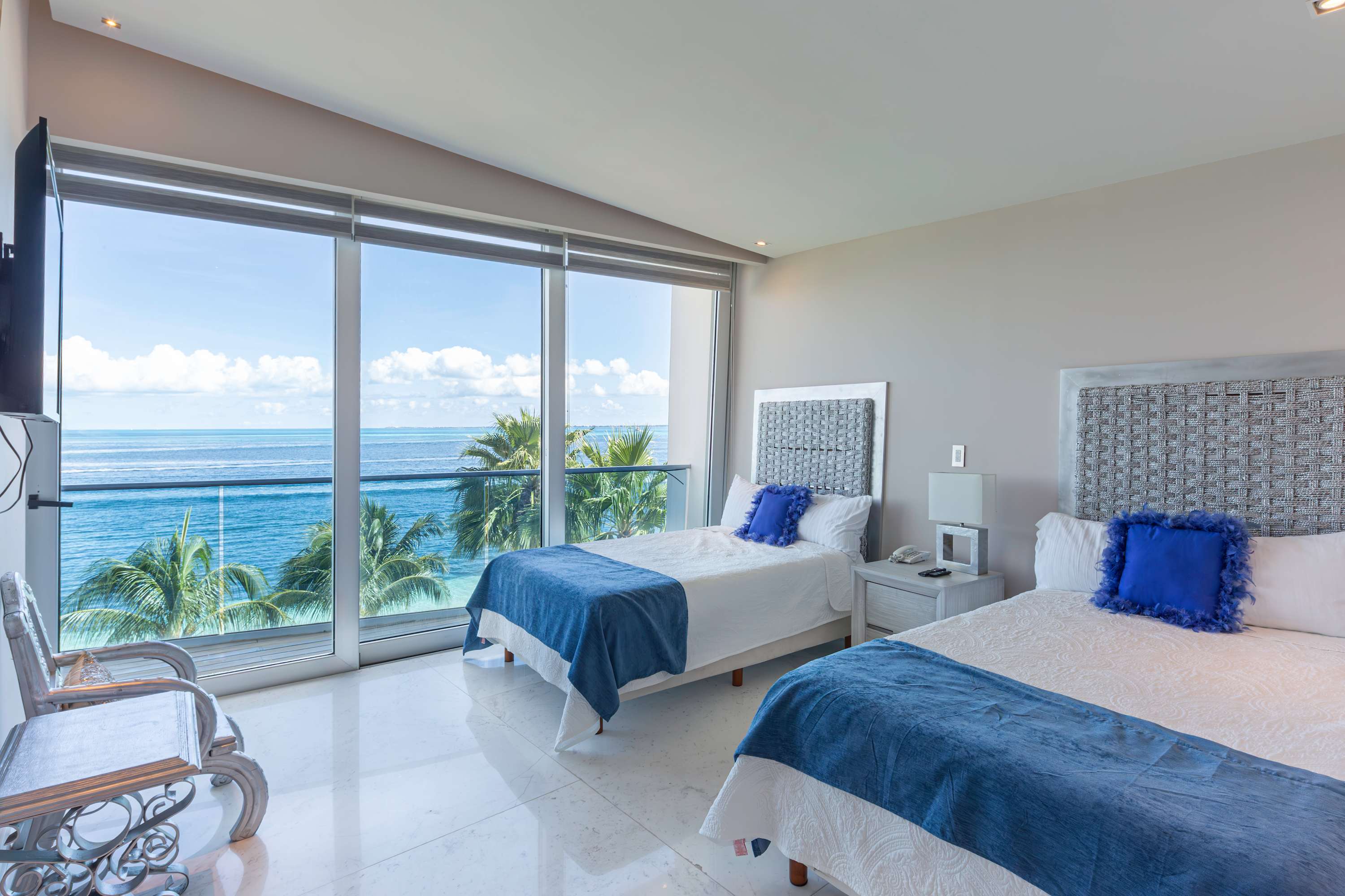A bedroom with two beds and a view of the ocean.