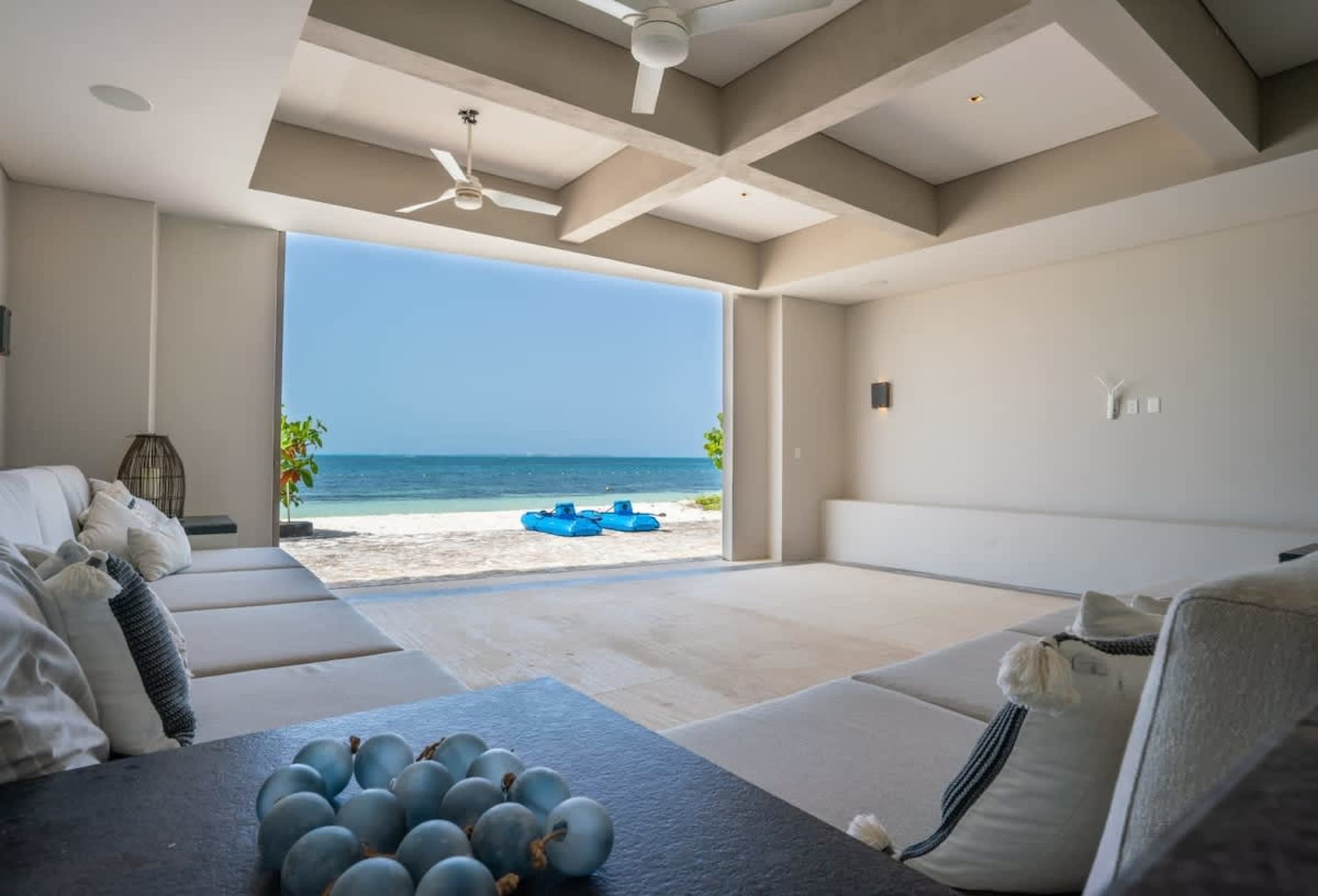 Interior of a living room with a large opening to a beach and ocean view.