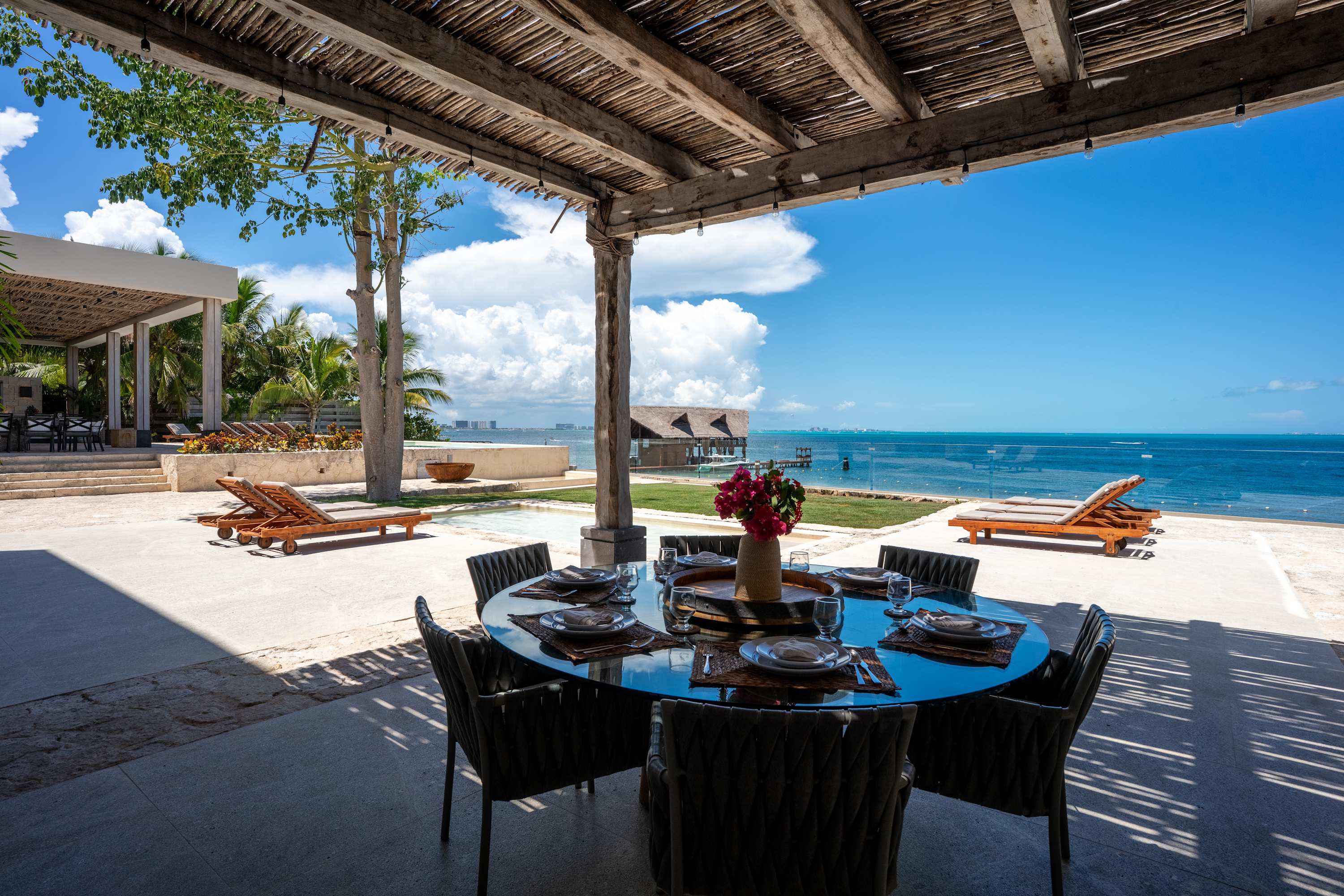 Outdoor dining area with a table set for dinner and a view of the ocean.