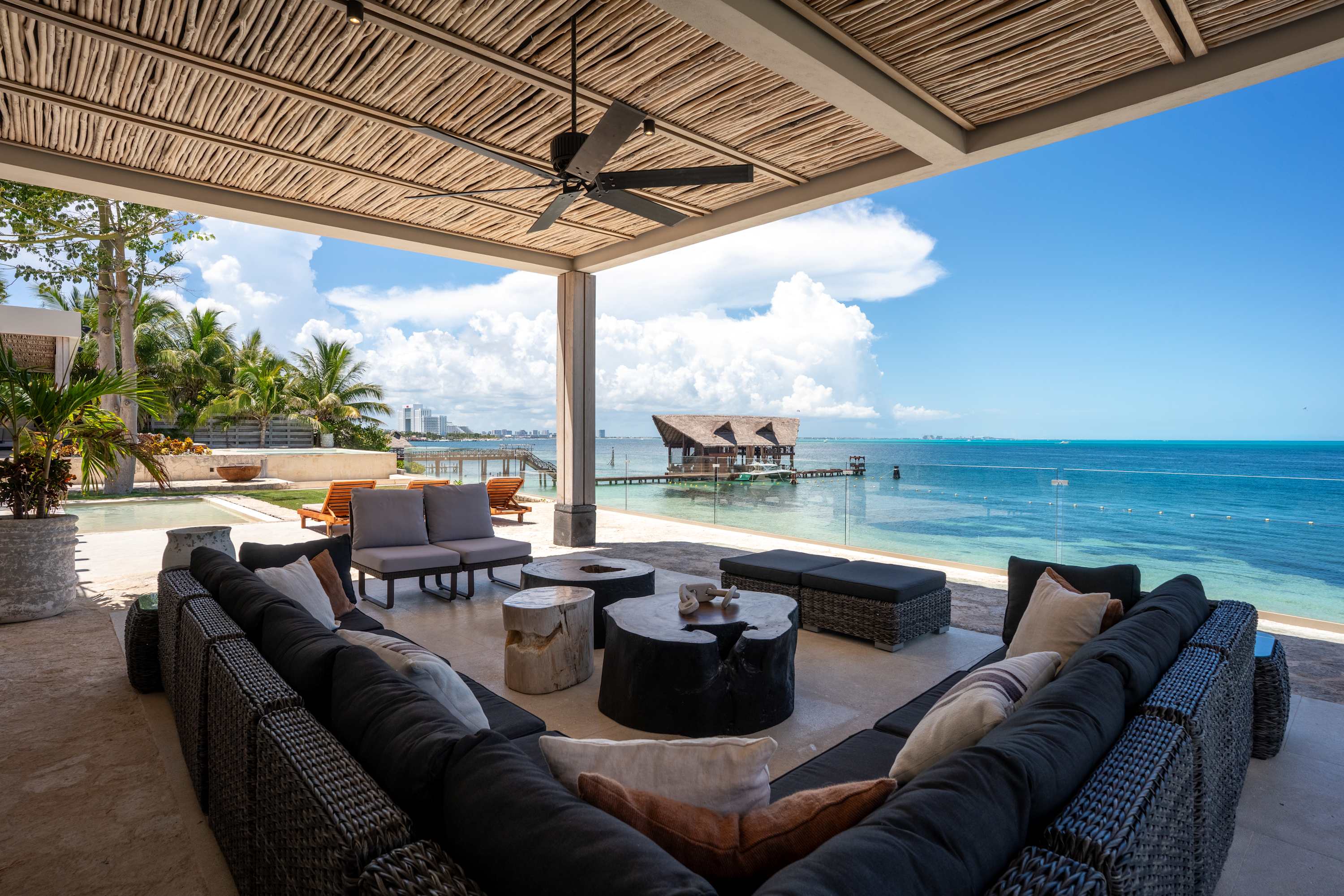 Outdoor living area with sectional sofa, coffee tables, and ocean view.