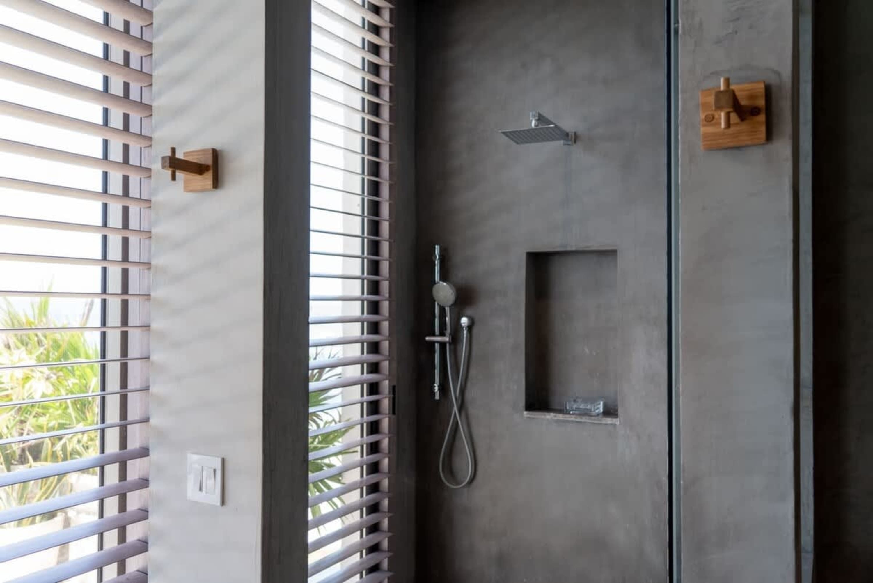 Modern grey shower with wood accents and blinds.