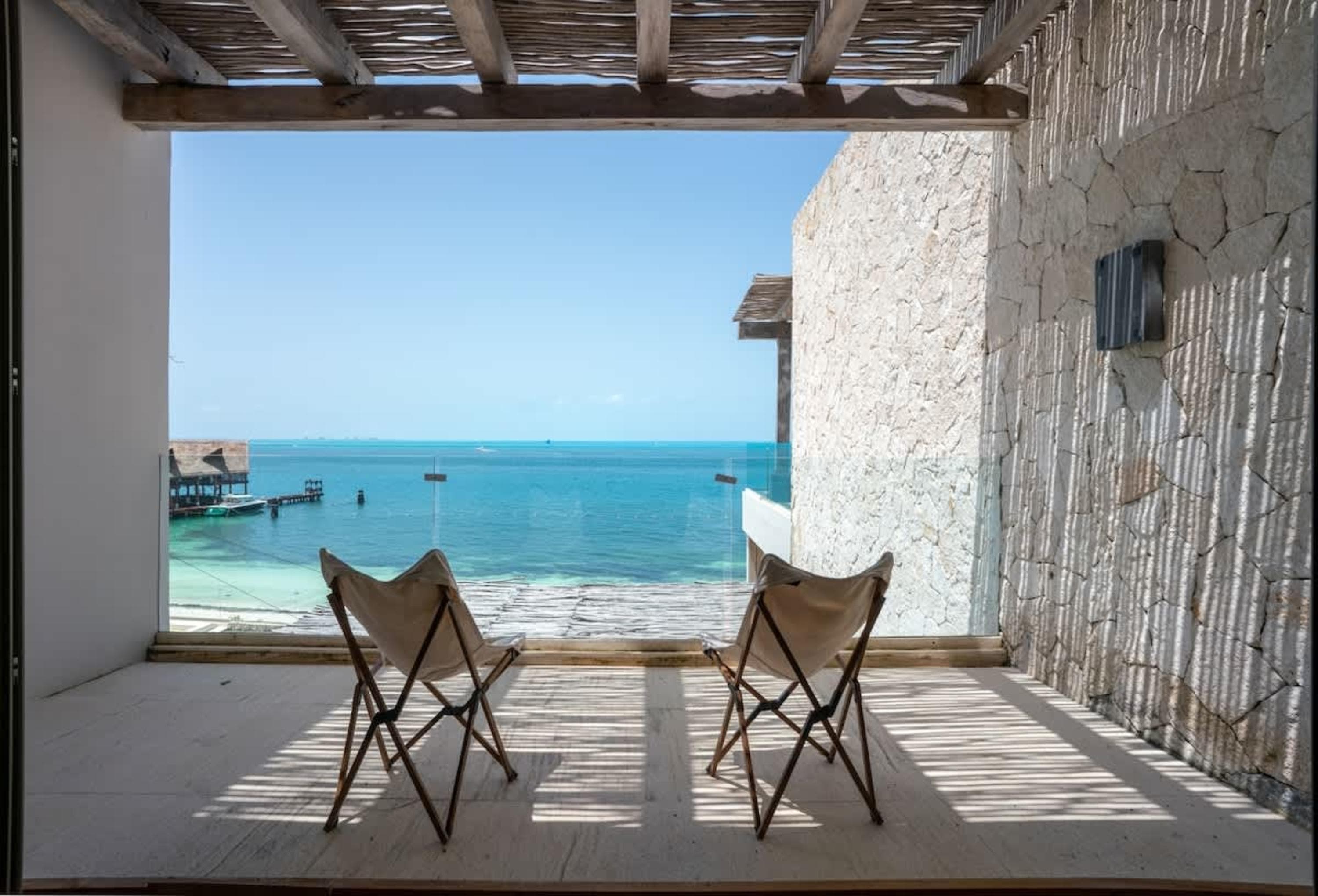 Two chairs on a balcony overlooking the ocean.