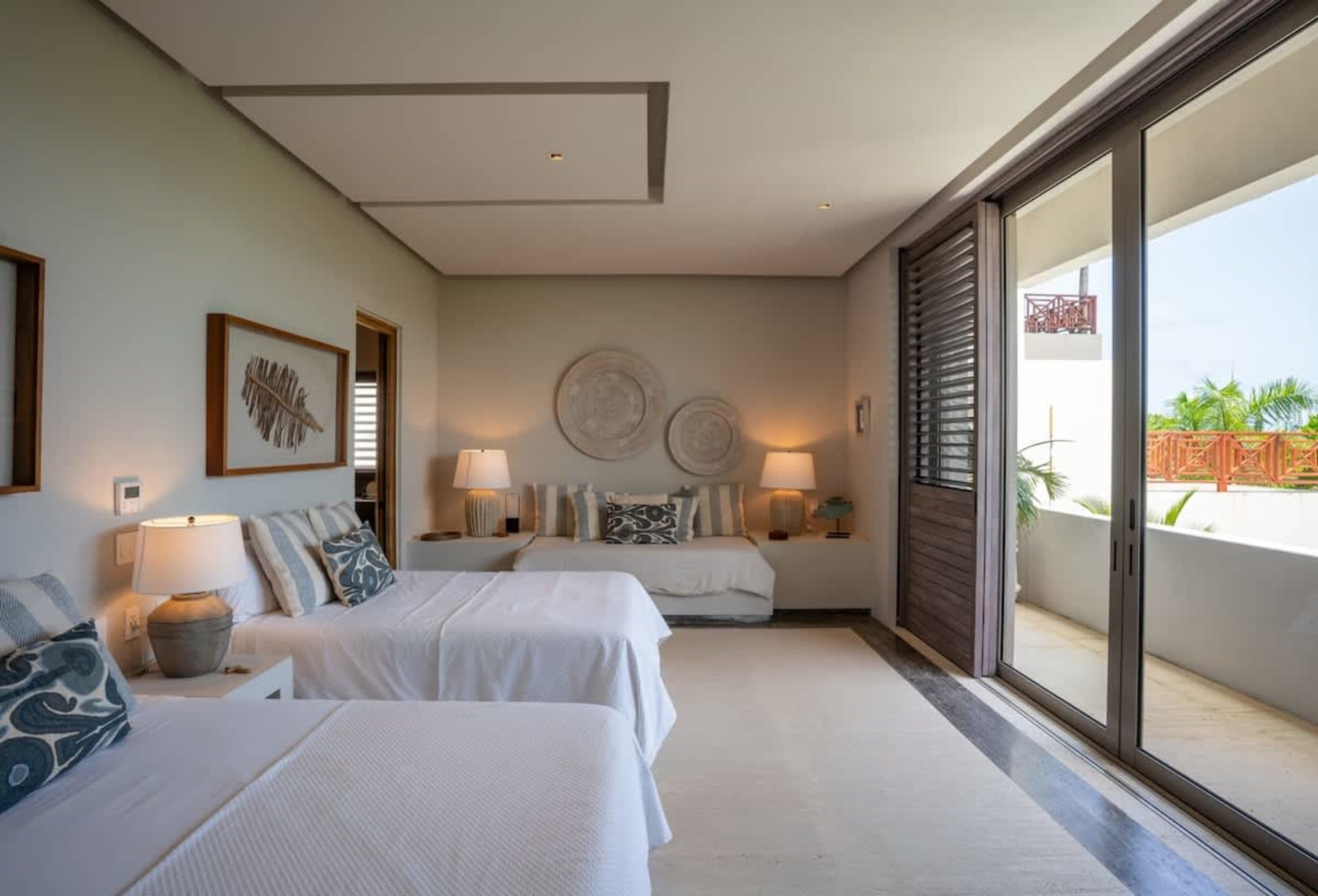 A bedroom with two beds, a daybed, and a balcony view.