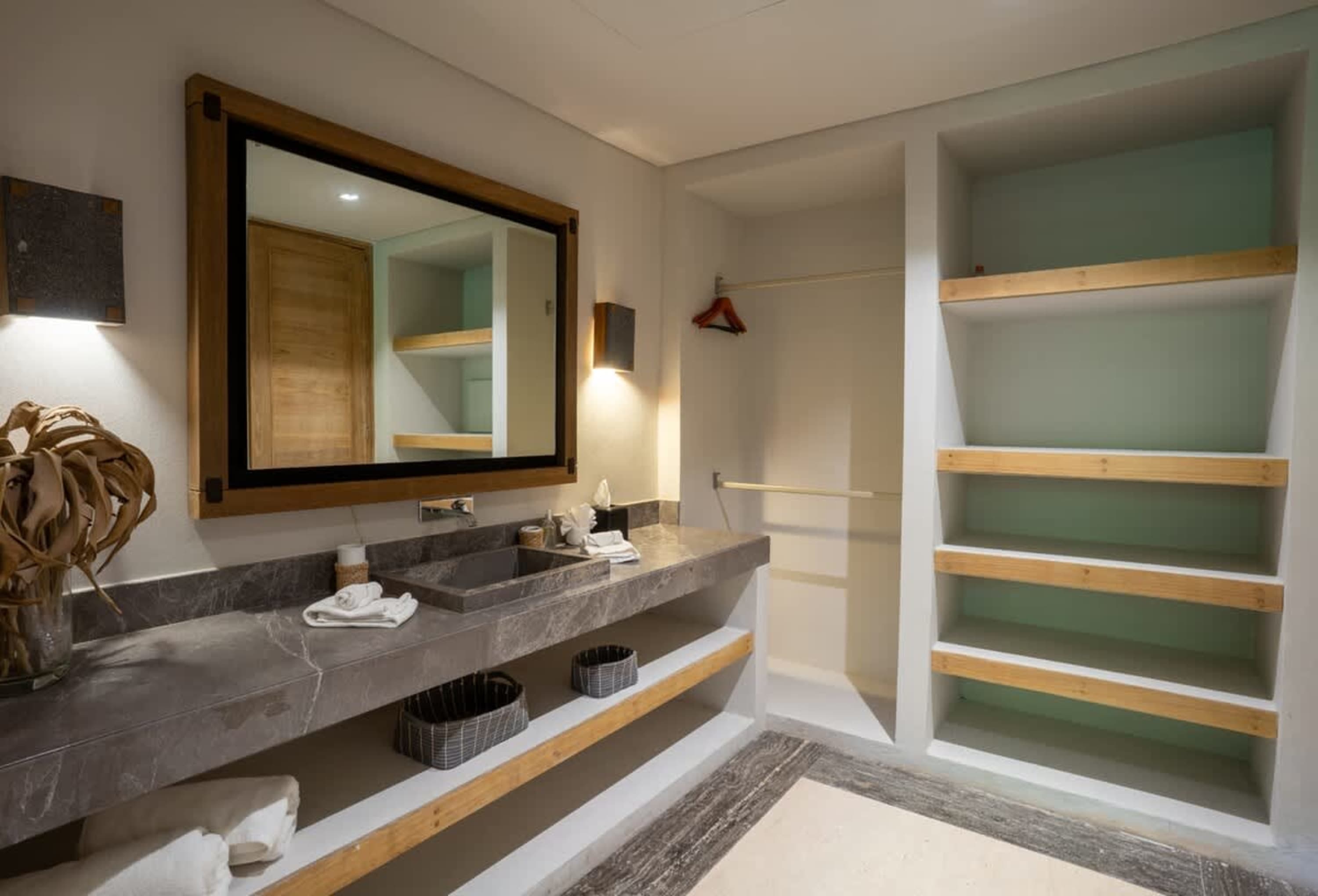 A luxurious bathroom with a marble vanity, large mirror, and open shelving.