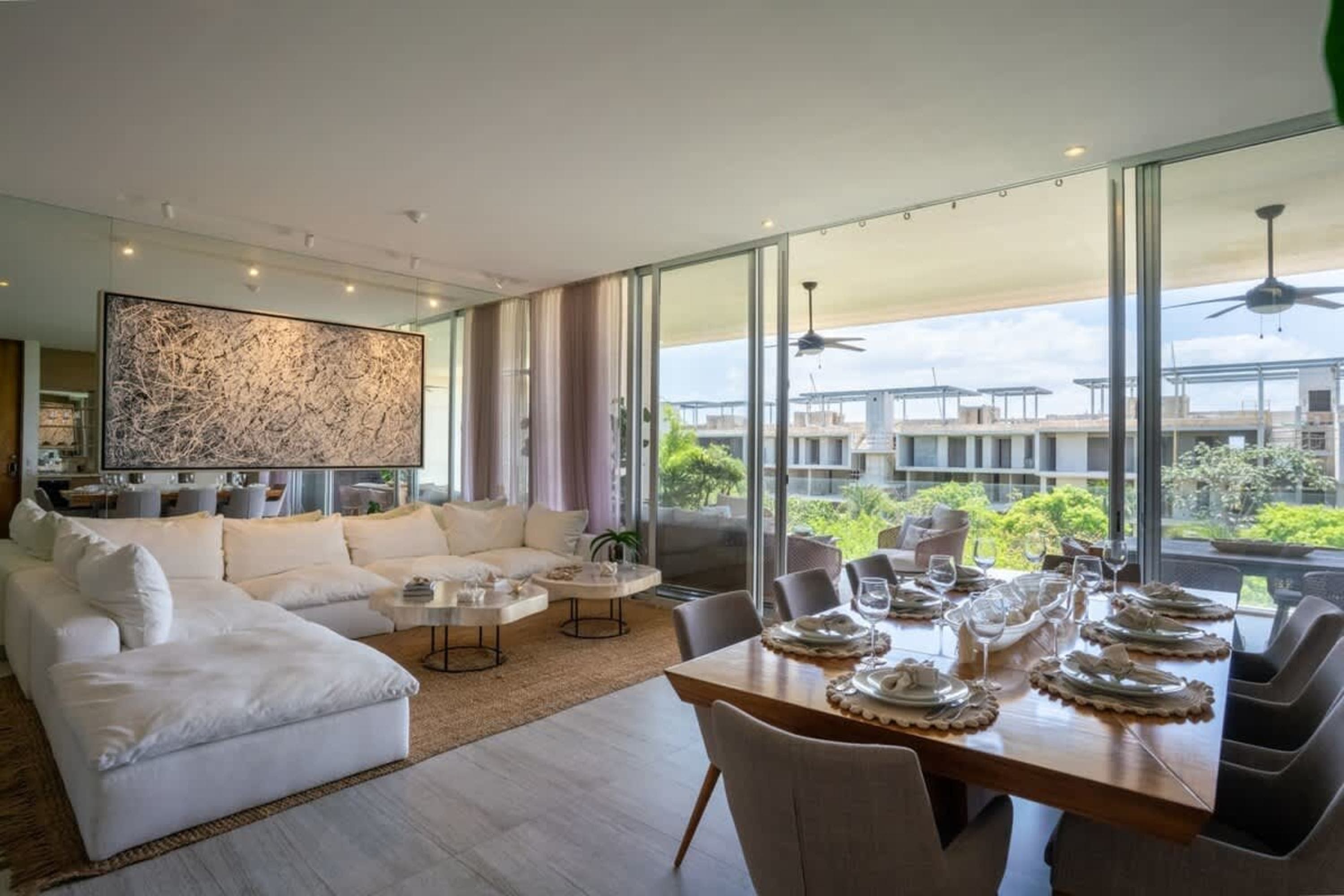 A modern living and dining room with white sectional sofa and dining table set for a meal.