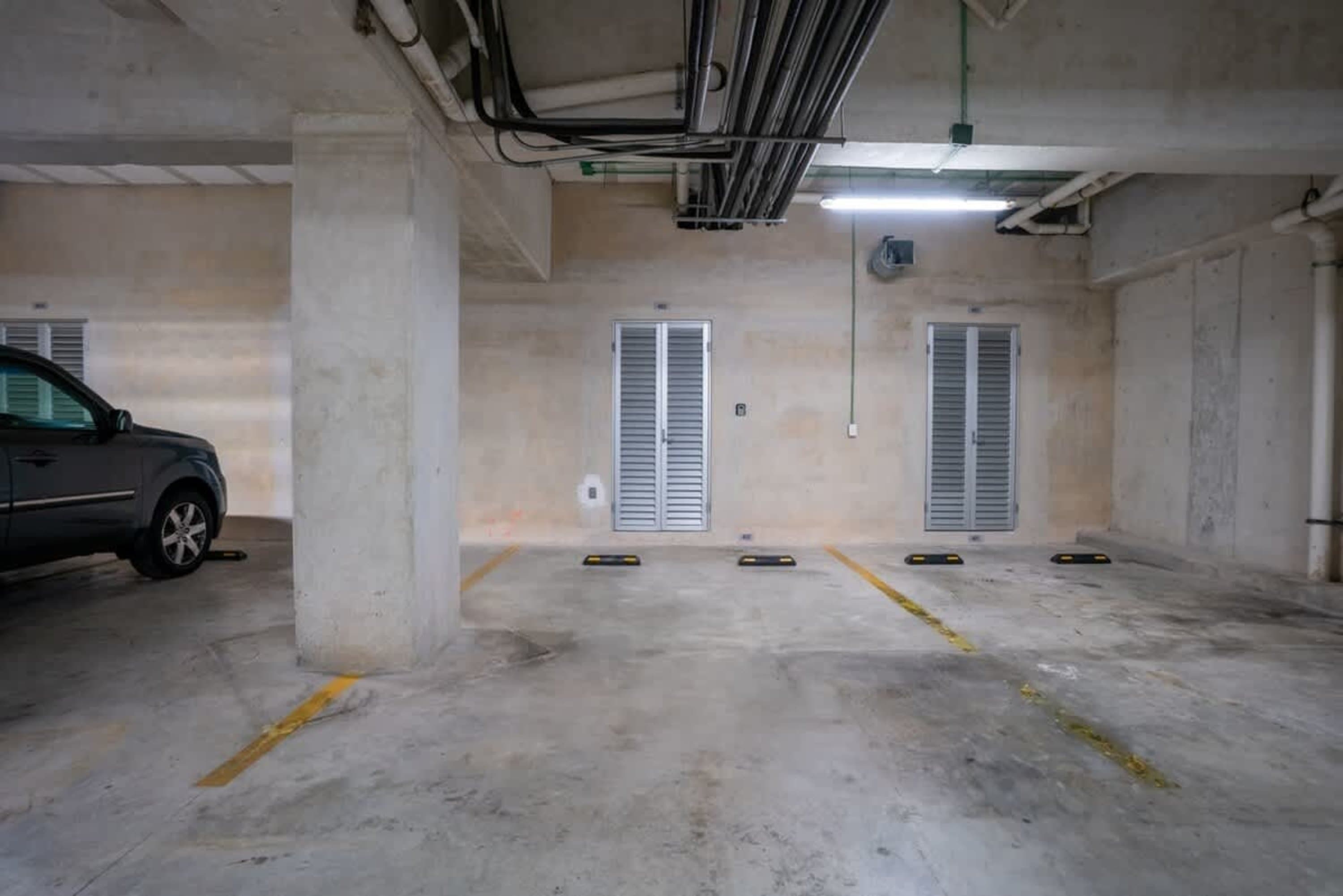 Parking garage with concrete floors, beige walls, and silver doors.