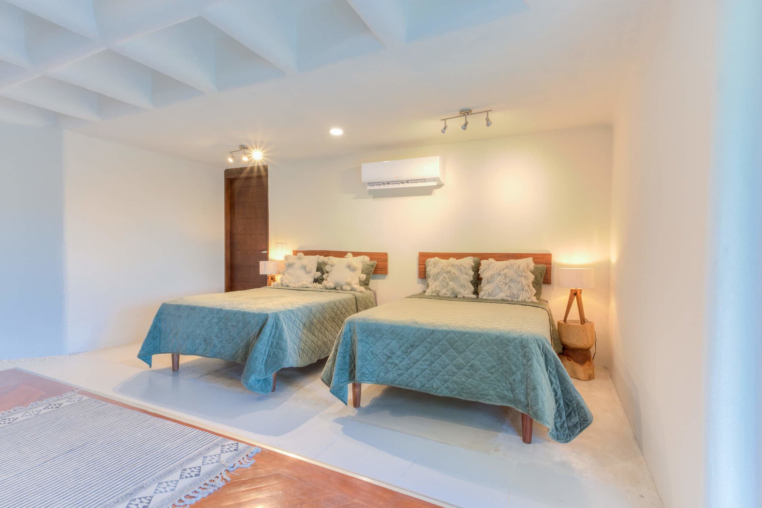 A bedroom with two beds, a wooden door, and an air conditioner.