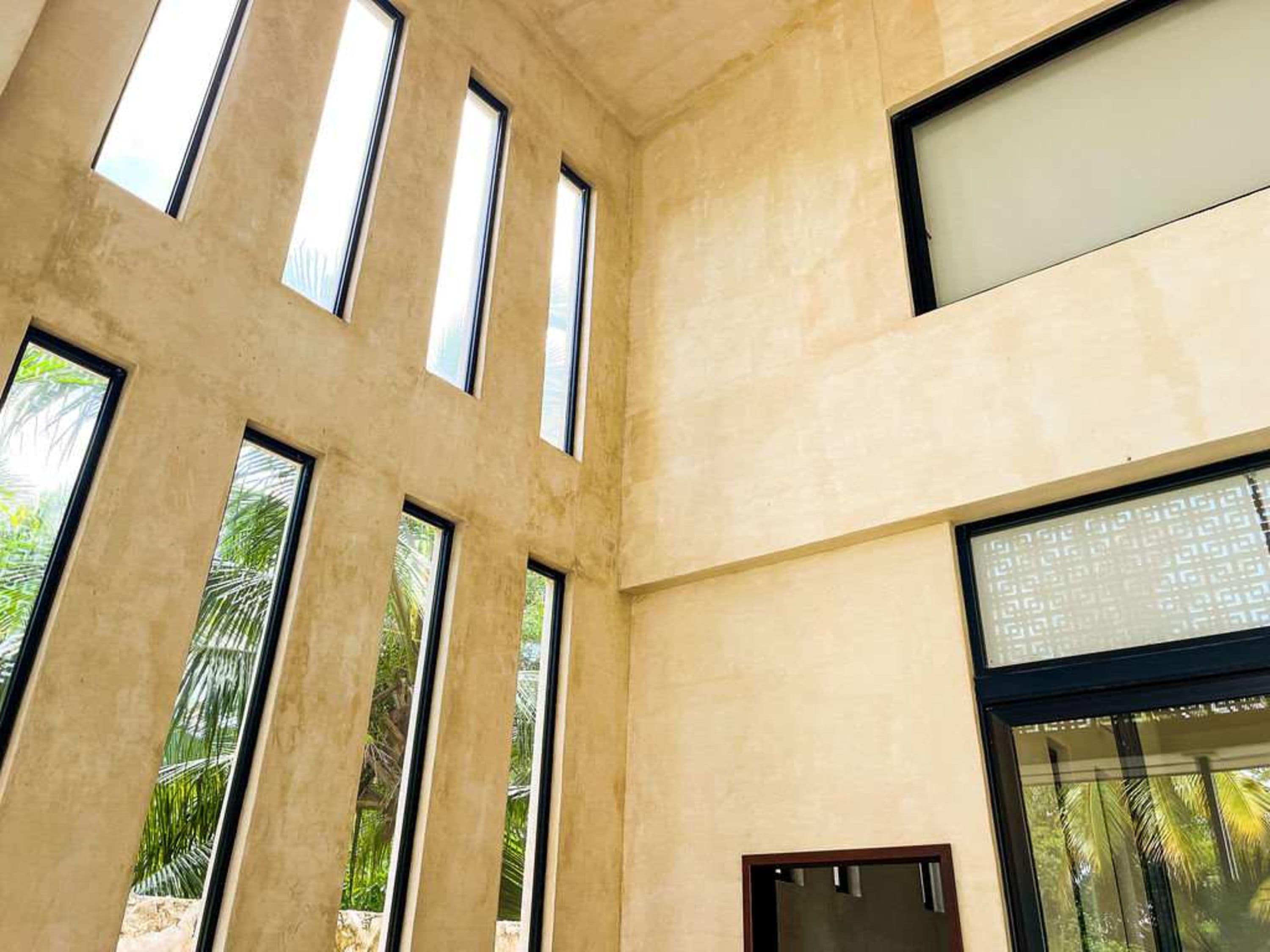 Modern building interior with tall windows overlooking palm trees.