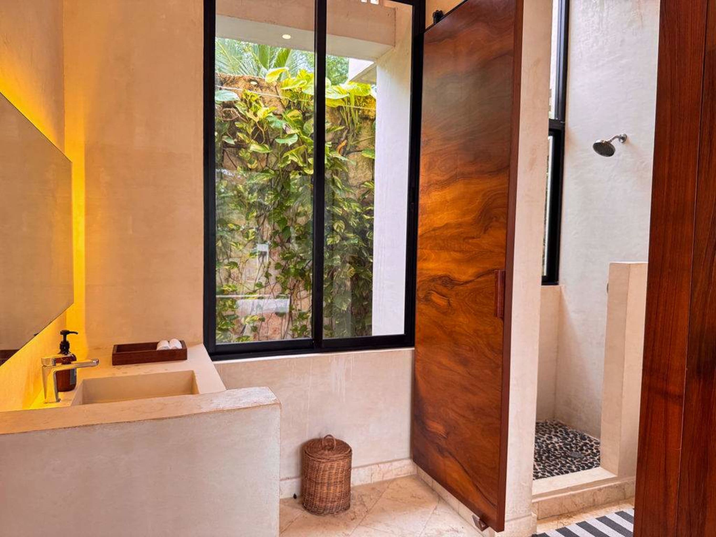 A bathroom with a sink, shower, and a large wooden door.