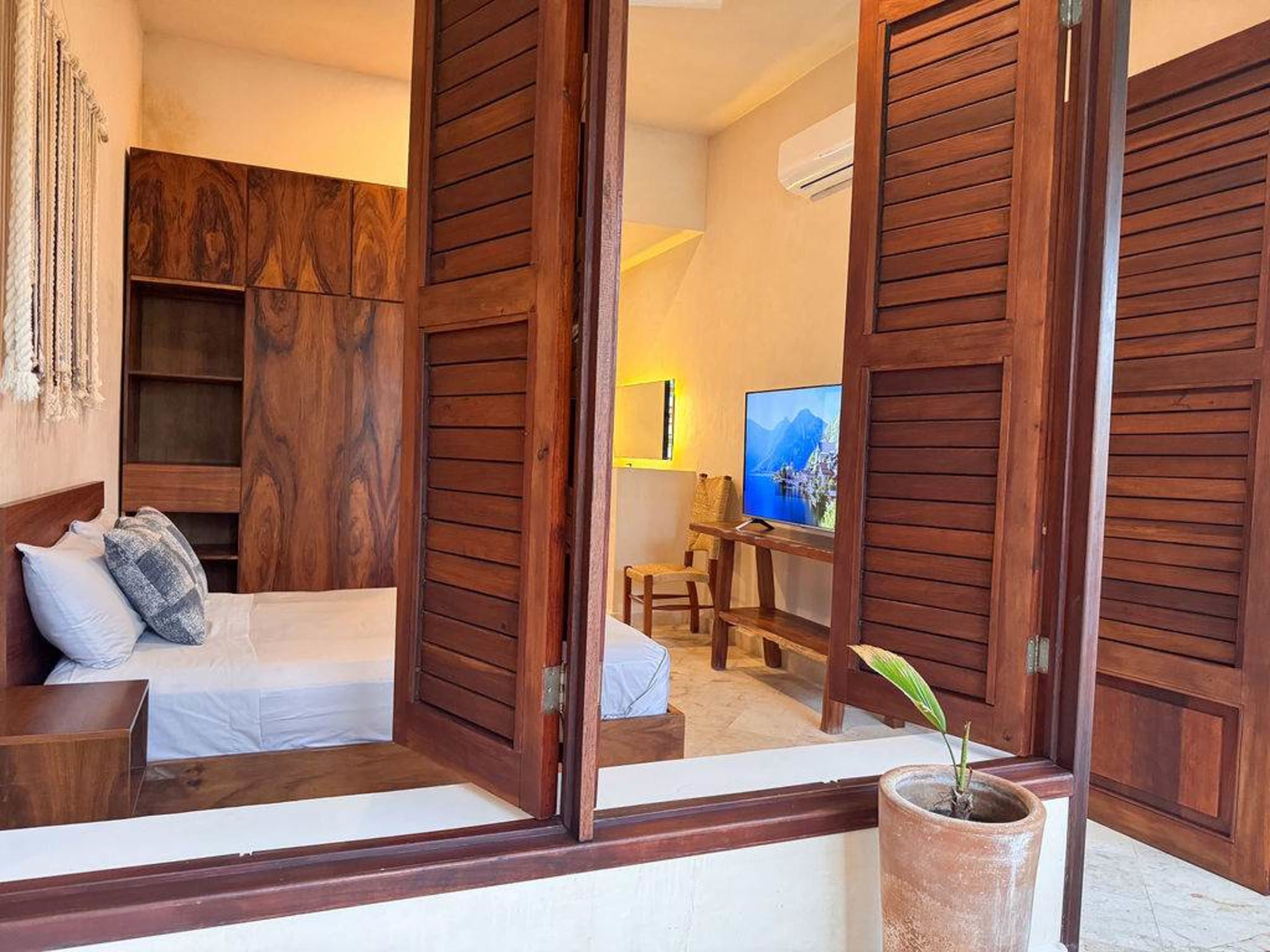 A bedroom with wooden furniture, a TV, and a bed.