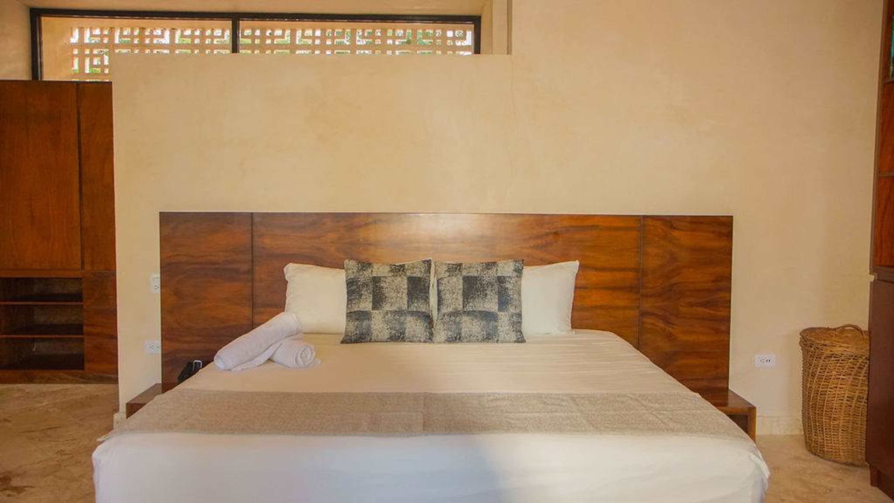 A bed with a wooden headboard, pillows, and rolled towels.