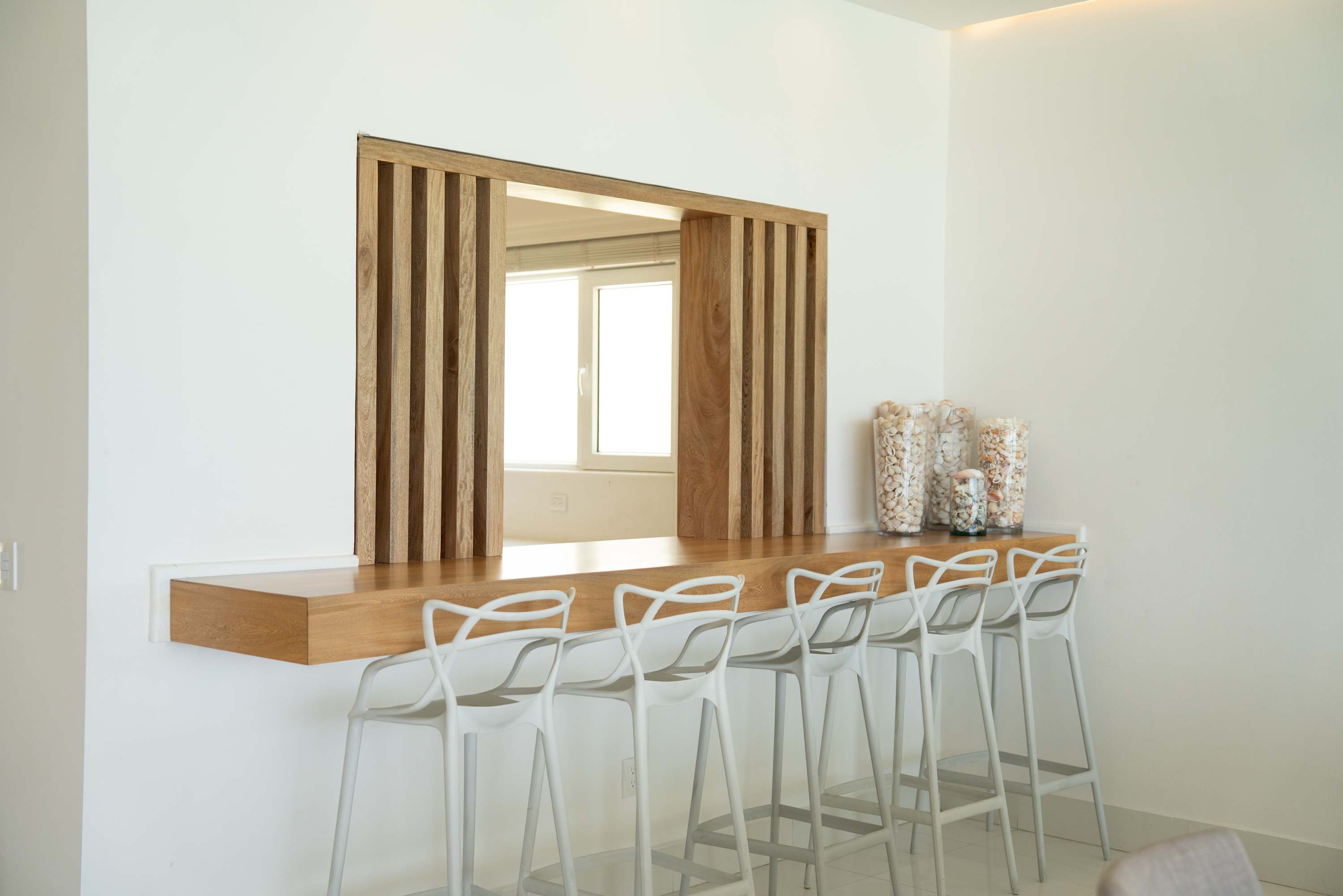 A modern bar with white stools and wooden accents.