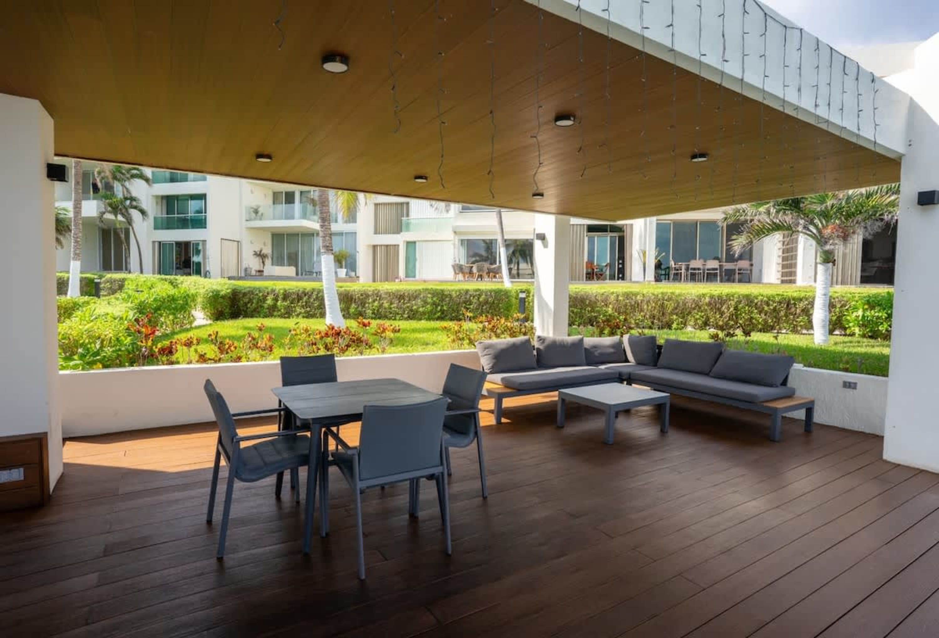 Outdoor patio with a dining set and a sectional sofa, overlooking a tropical garden.