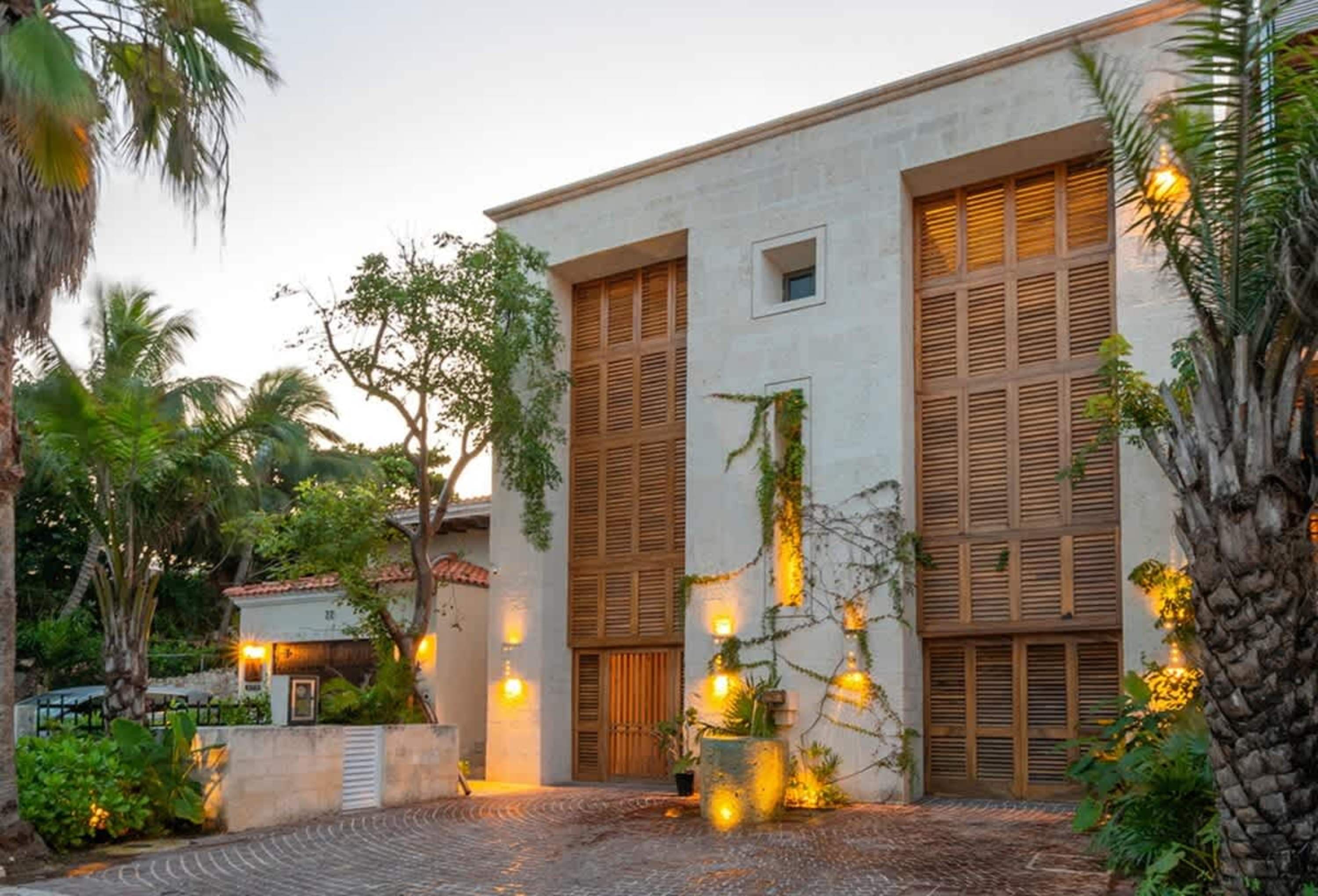 Modern house with wooden shutters and tropical landscaping.