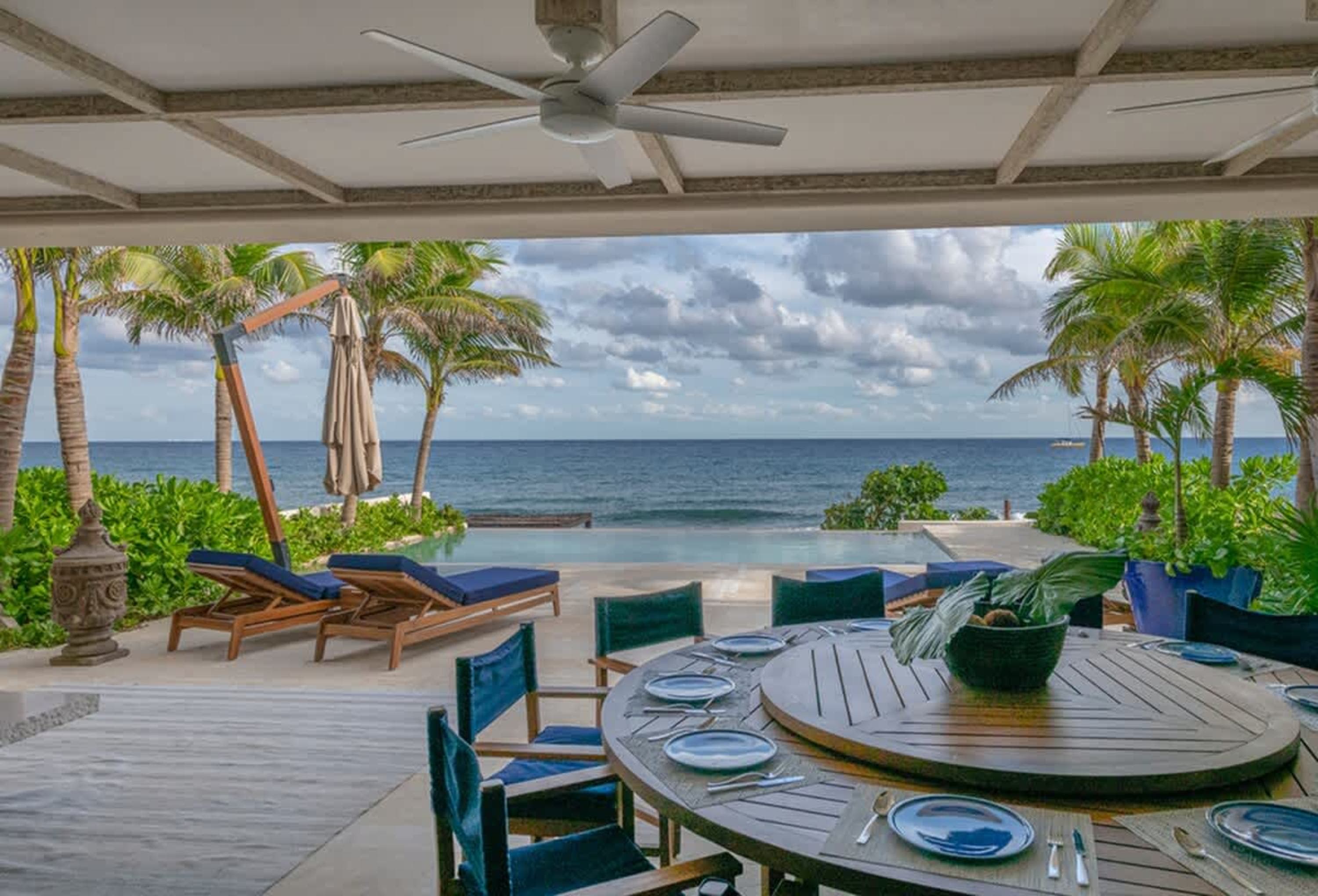 A covered patio overlooks a swimming pool and the ocean.