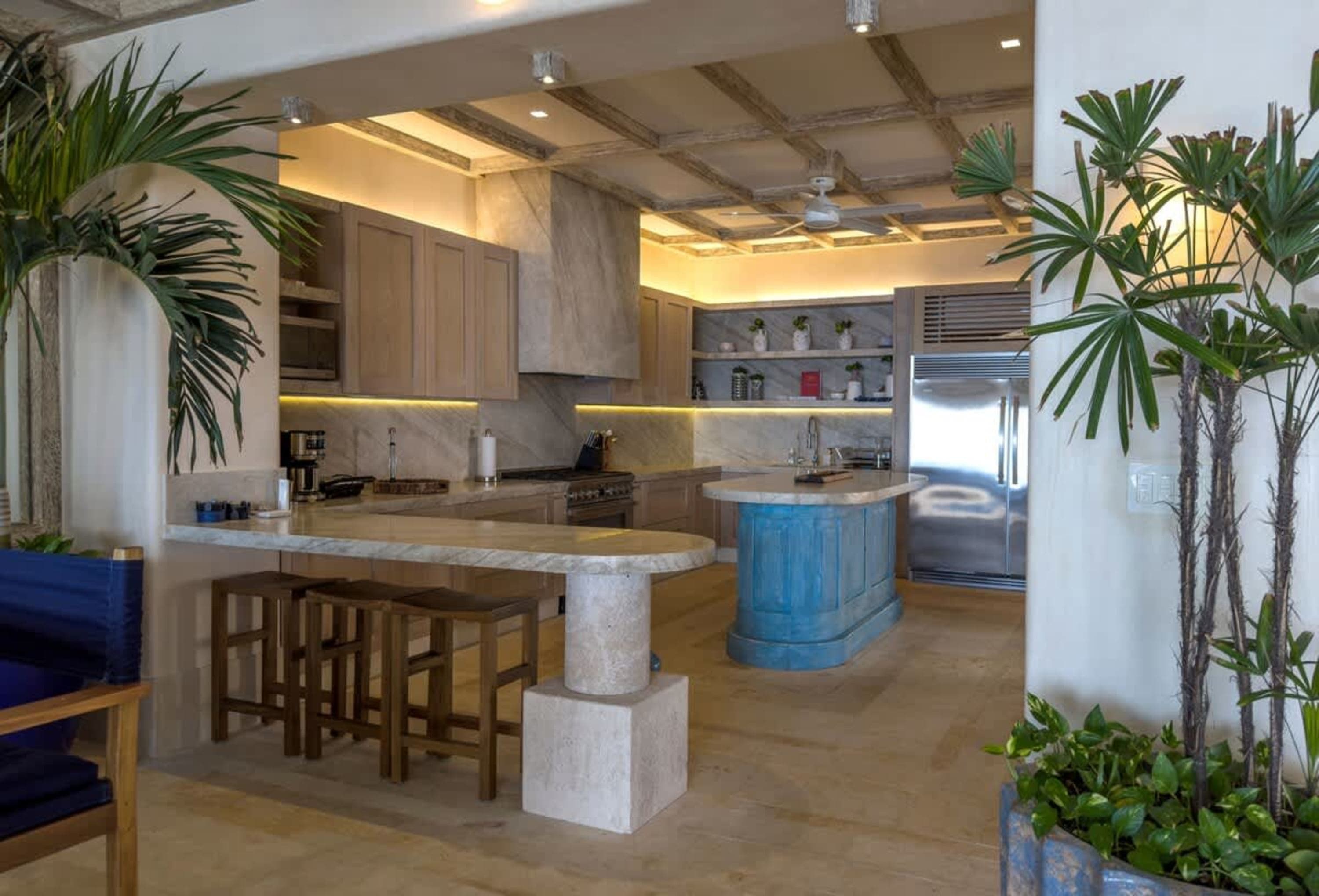 Stylish kitchen with a blue island, a large refrigerator, and wooden bar stools.