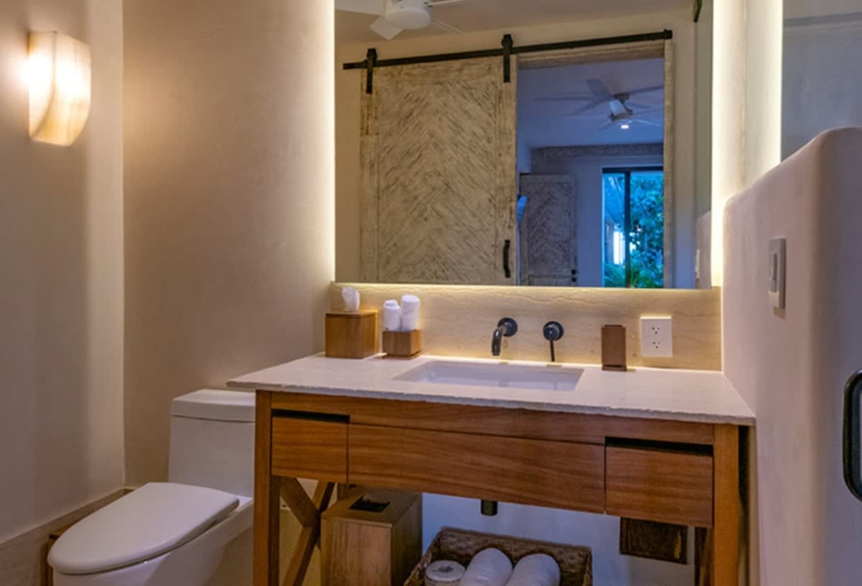 A modern bathroom with a wooden vanity, a sink, and a toilet.
