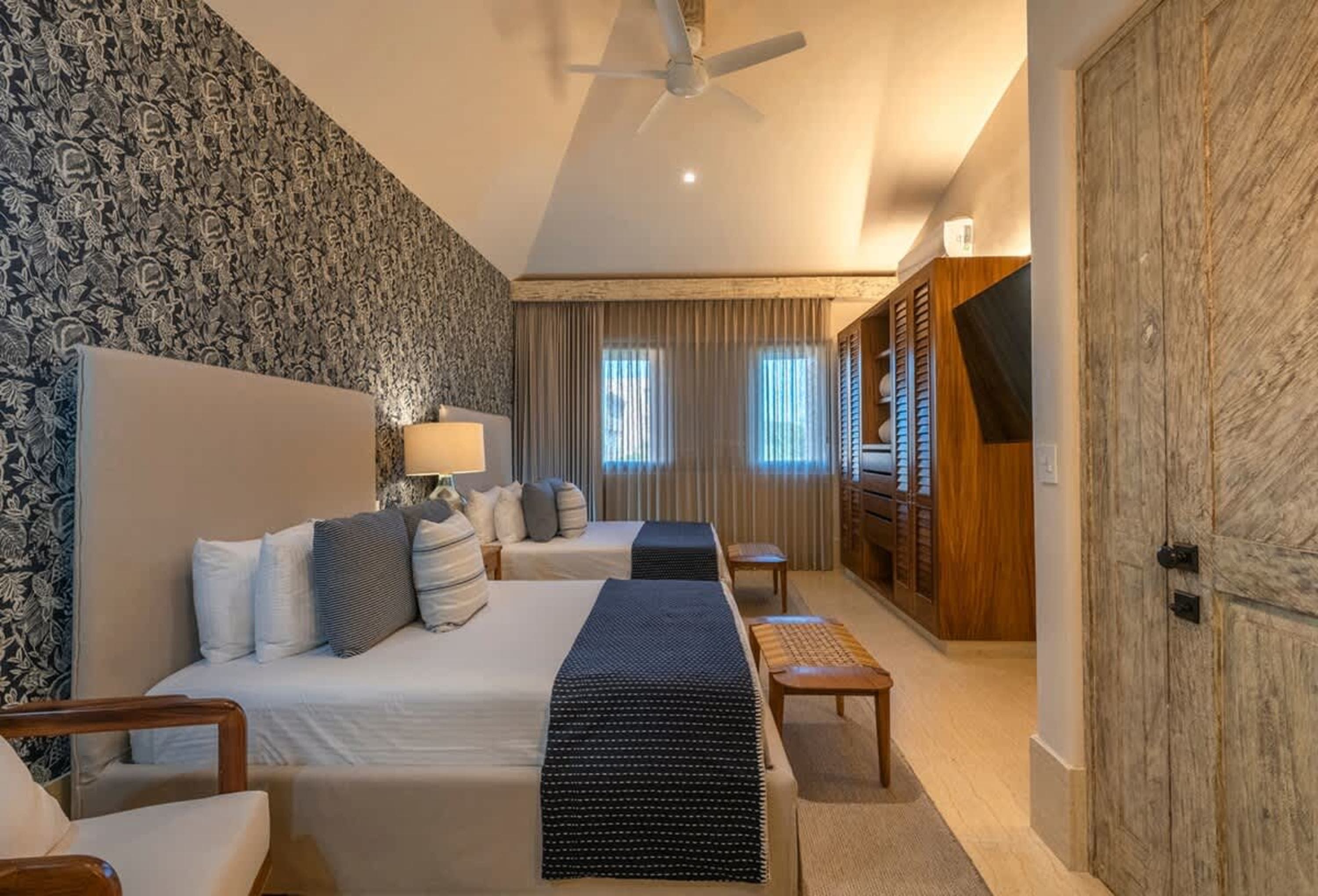 Bedroom with two beds, floral wallpaper, and a wooden wardrobe.