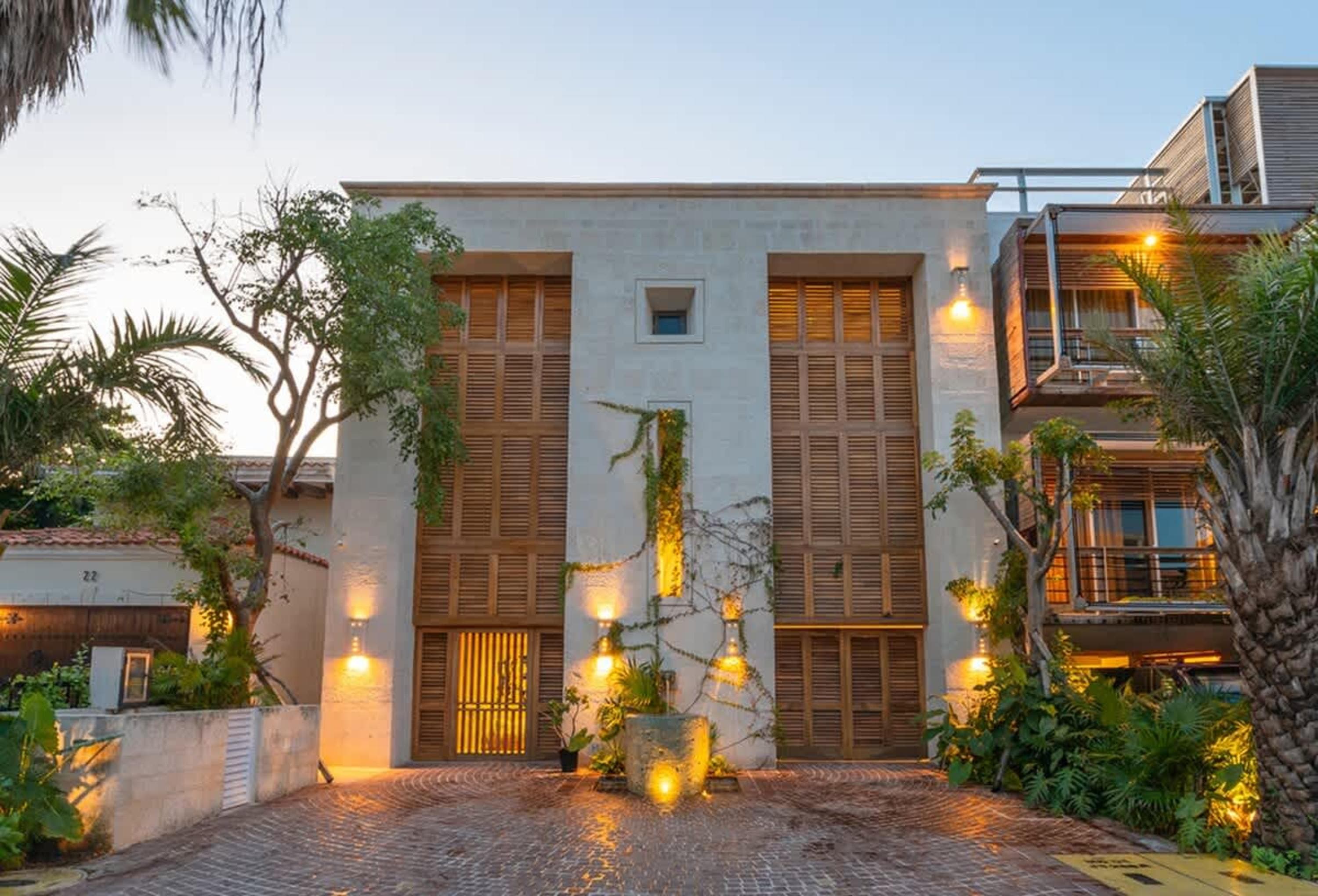 A modern house with wooden shutters and tropical plants.