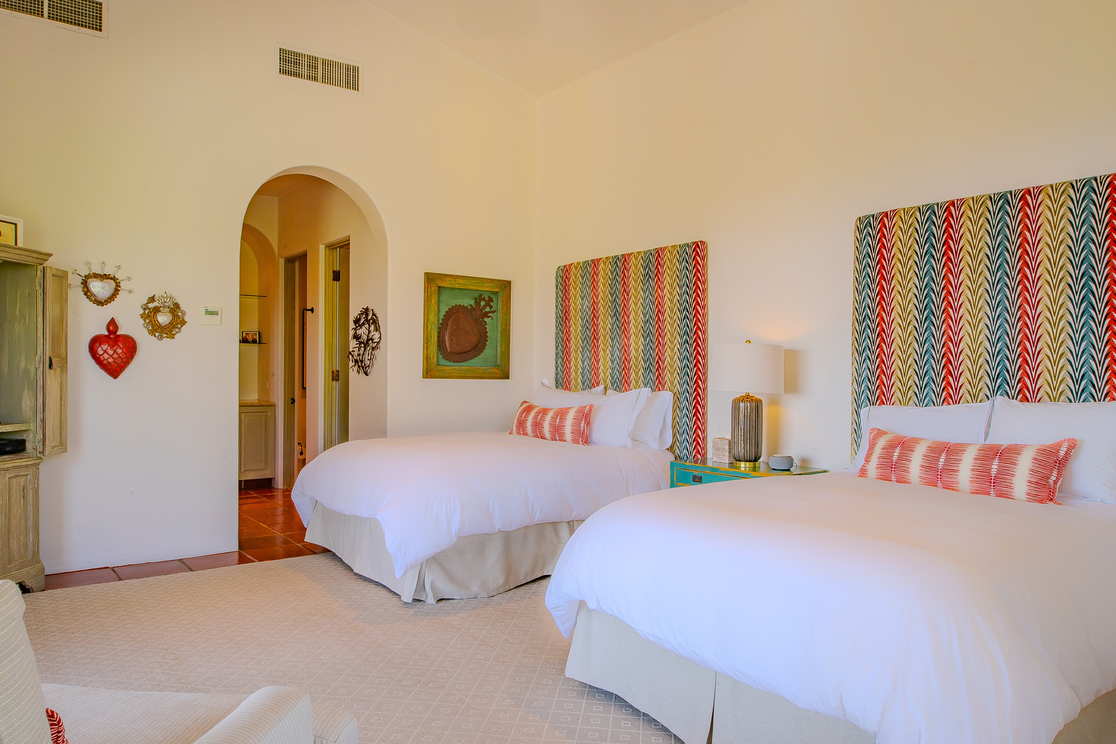 Bedroom 2 · Unwind in your bright, cheerful bedroom with two plush beds dressed in crisp linens and vibrant patterned headboards that add personality to your space. Charming decor and soothing earth tones create warmth.