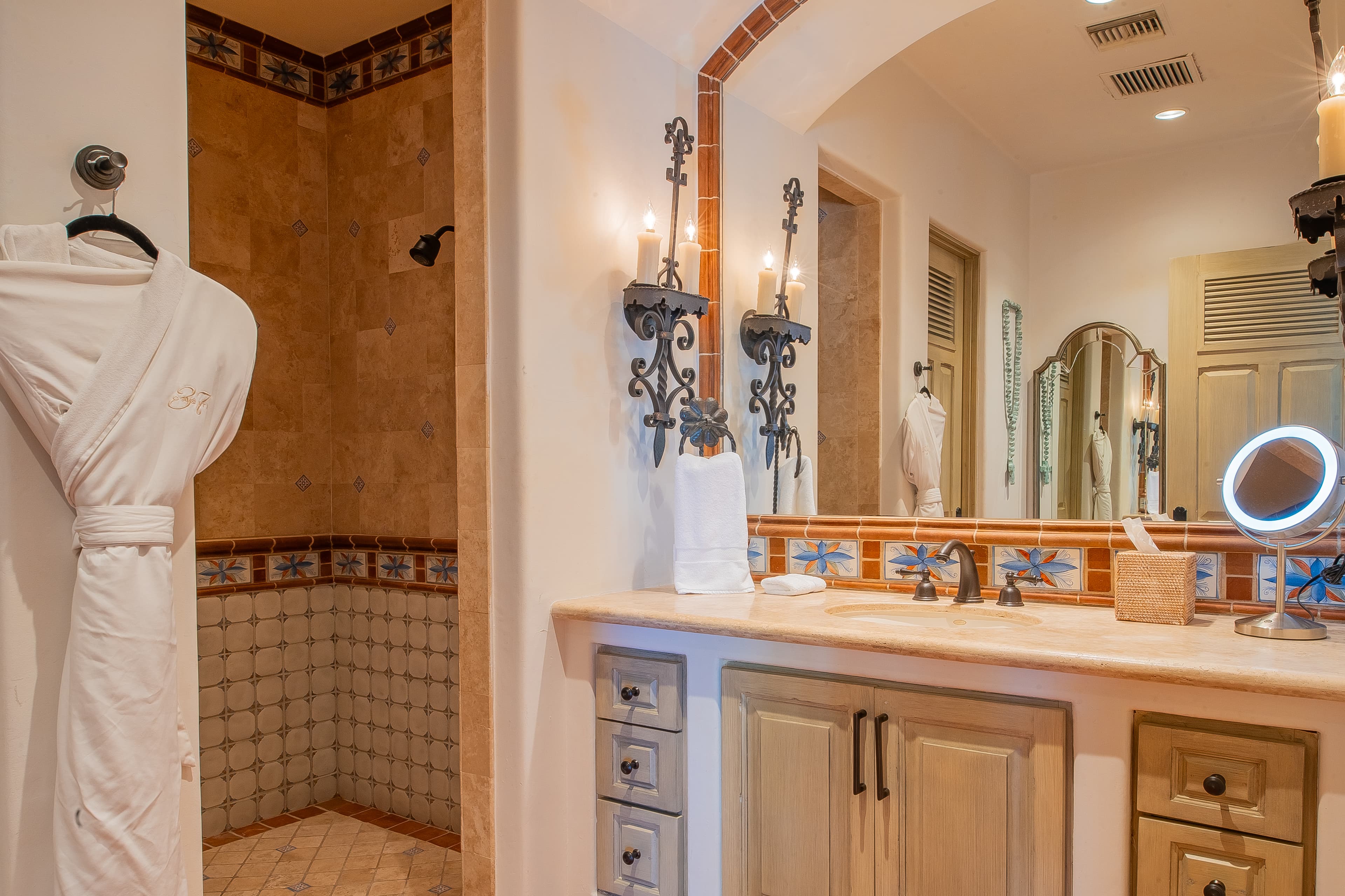 Bathroom 3 · Your elegant bathroom features a spacious walk-in shower with decorative tilework, a well-appointed vanity, and plush robes awaiting your arrival for the ultimate comfort.
