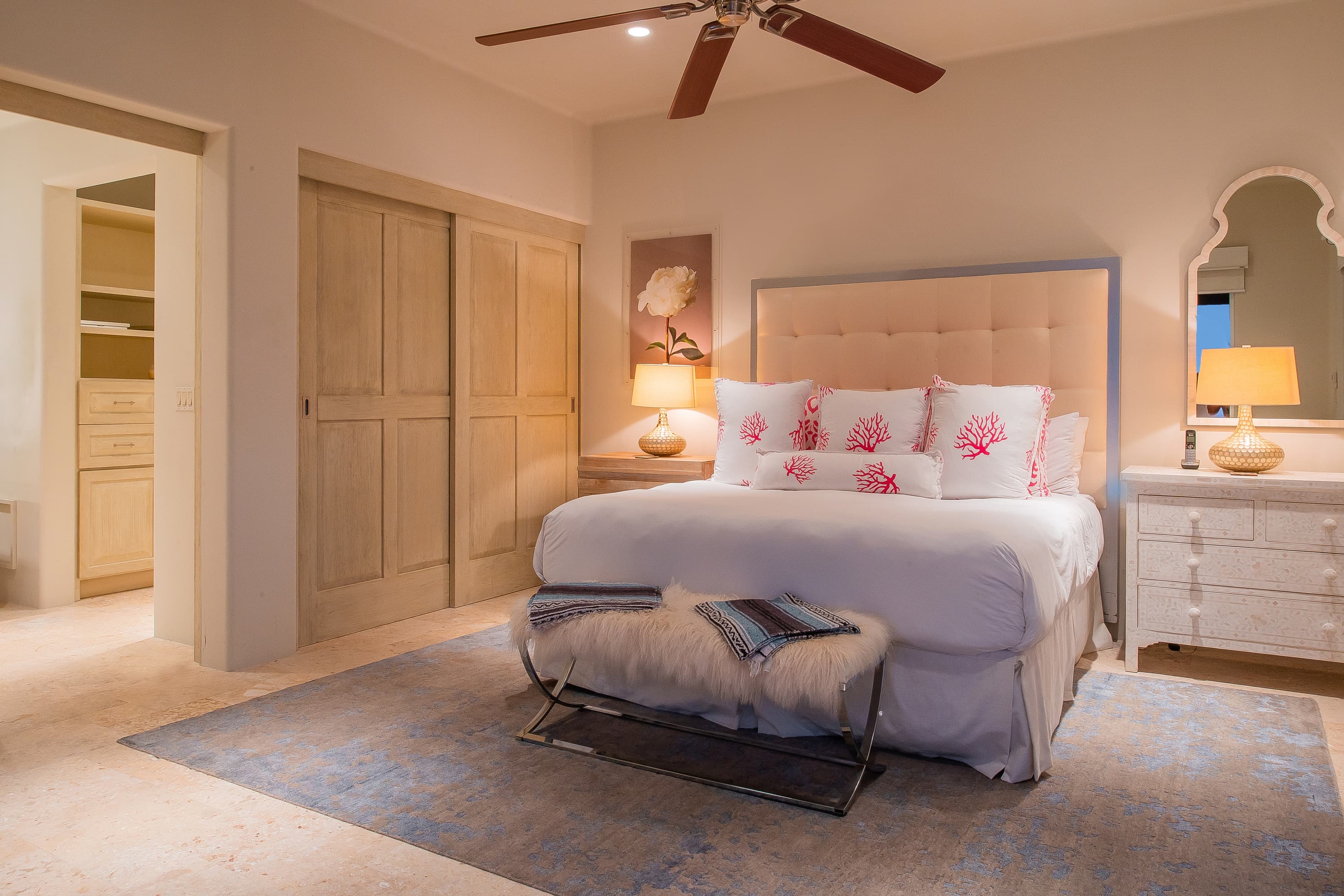 Large bed with a bench in front, flanked on either side by nightstands.