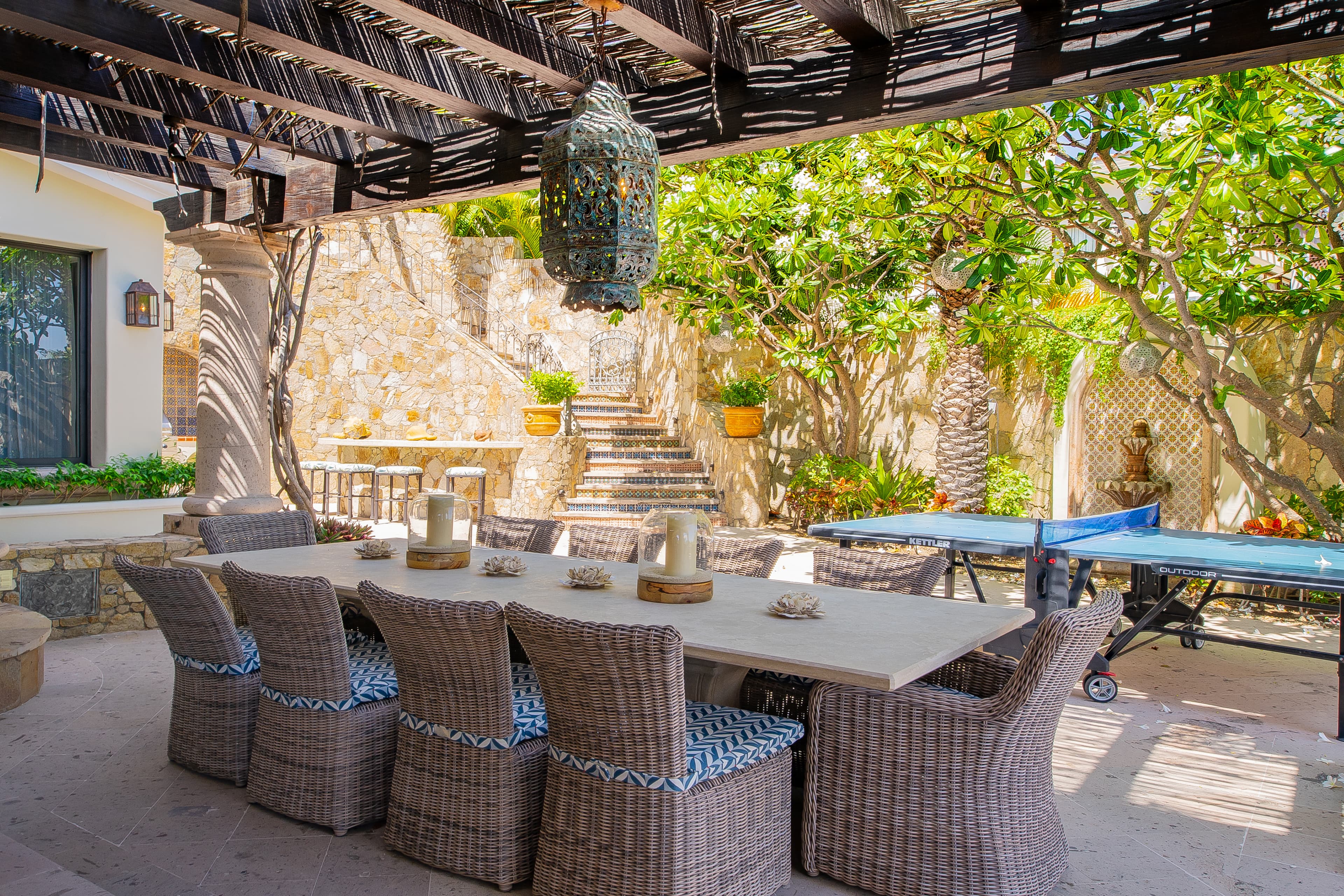 Picture yourself dining under rustic wooden beams, surrounded by lush greenery and dappled sunlight, at this charming outdoor retreat—perfect for memorable meals and lively gatherings.