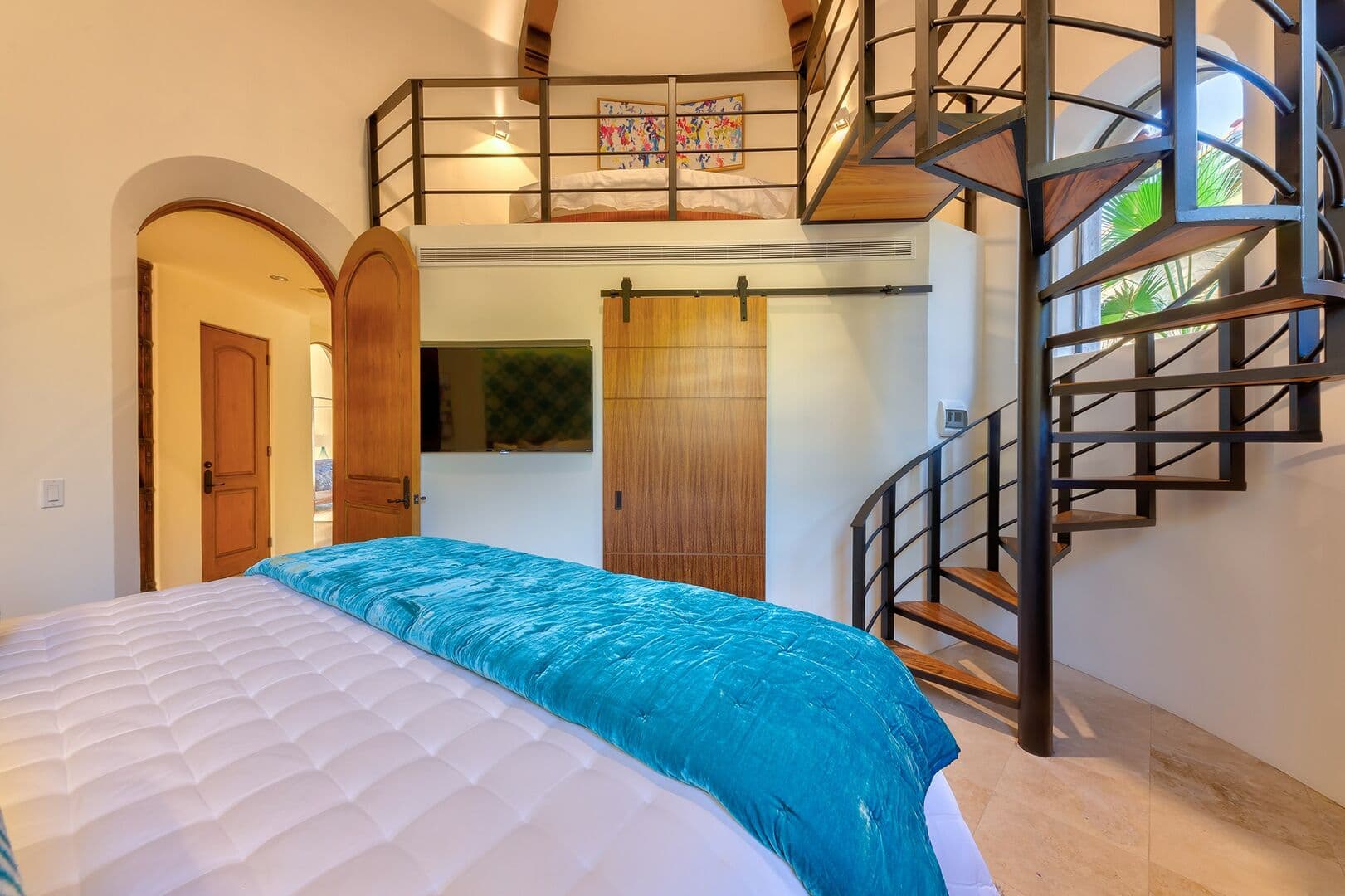 A view of the spiral staircase in bedroom 3 with a bed up in the loft.