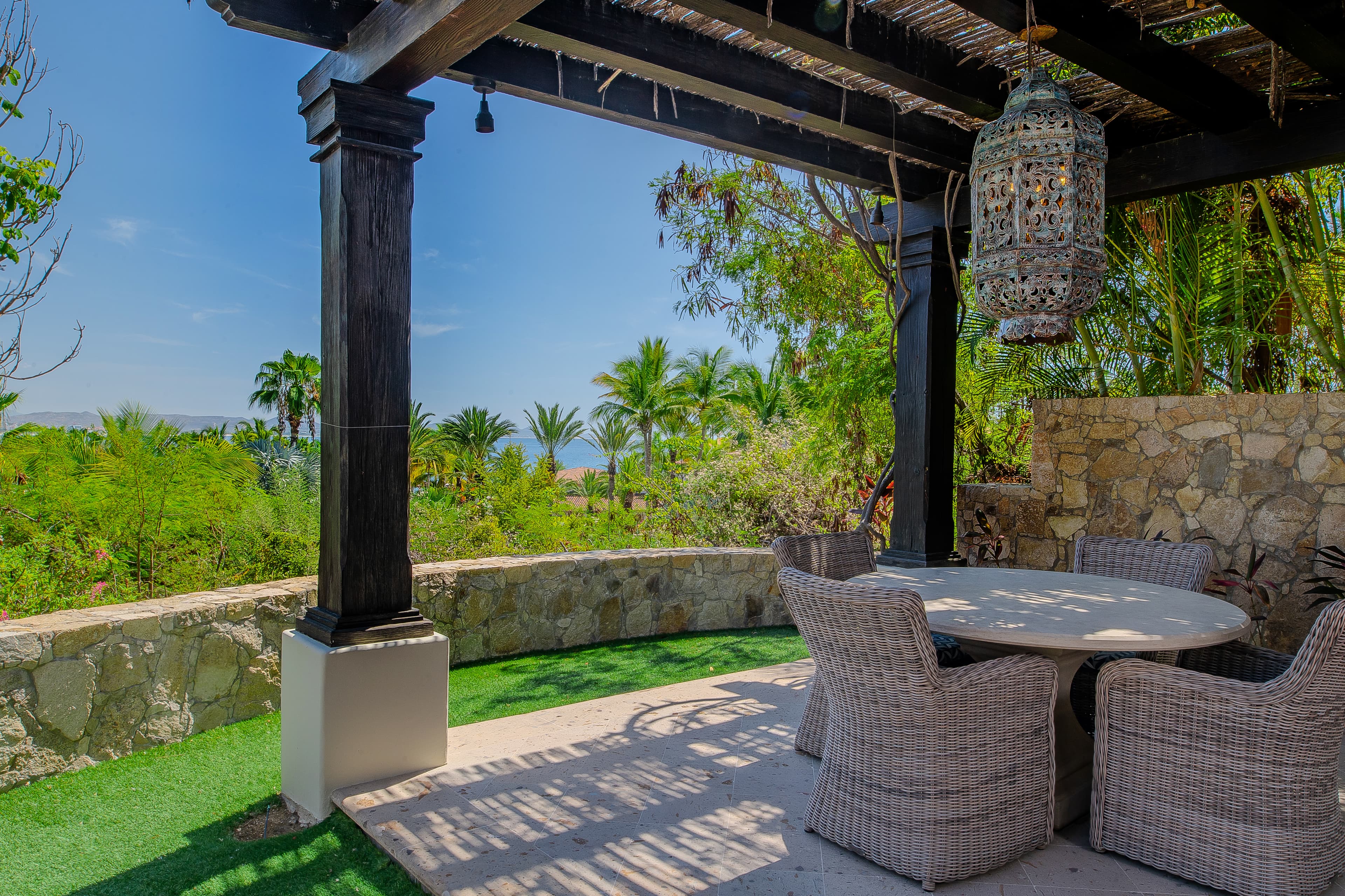 Unwind under the shaded pergola at this serene outdoor dining spot, where ocean breezes meet lush tropical views. Your peaceful oasis awaits.