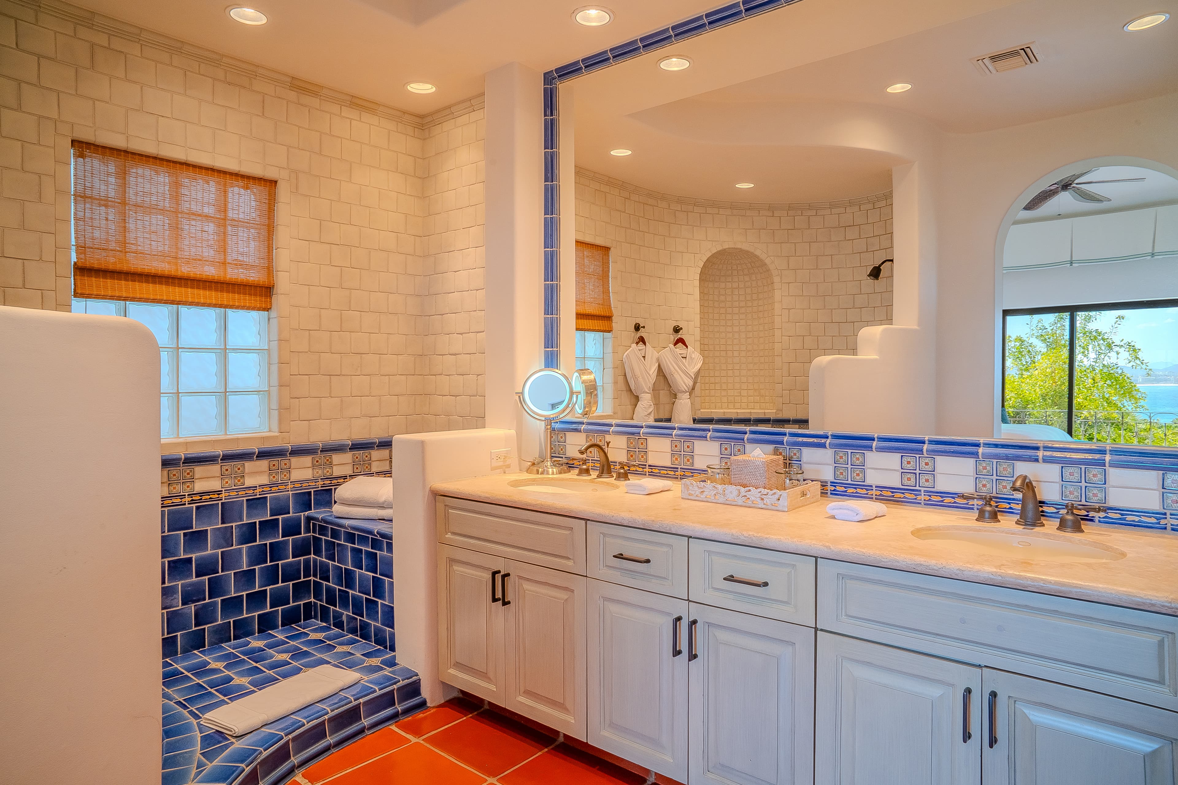 Bathroom 2 · Vibrant blue and white tilework meets soft robes and a soaking tub—your private spa retreat awaits in this beautifully lit bathroom.