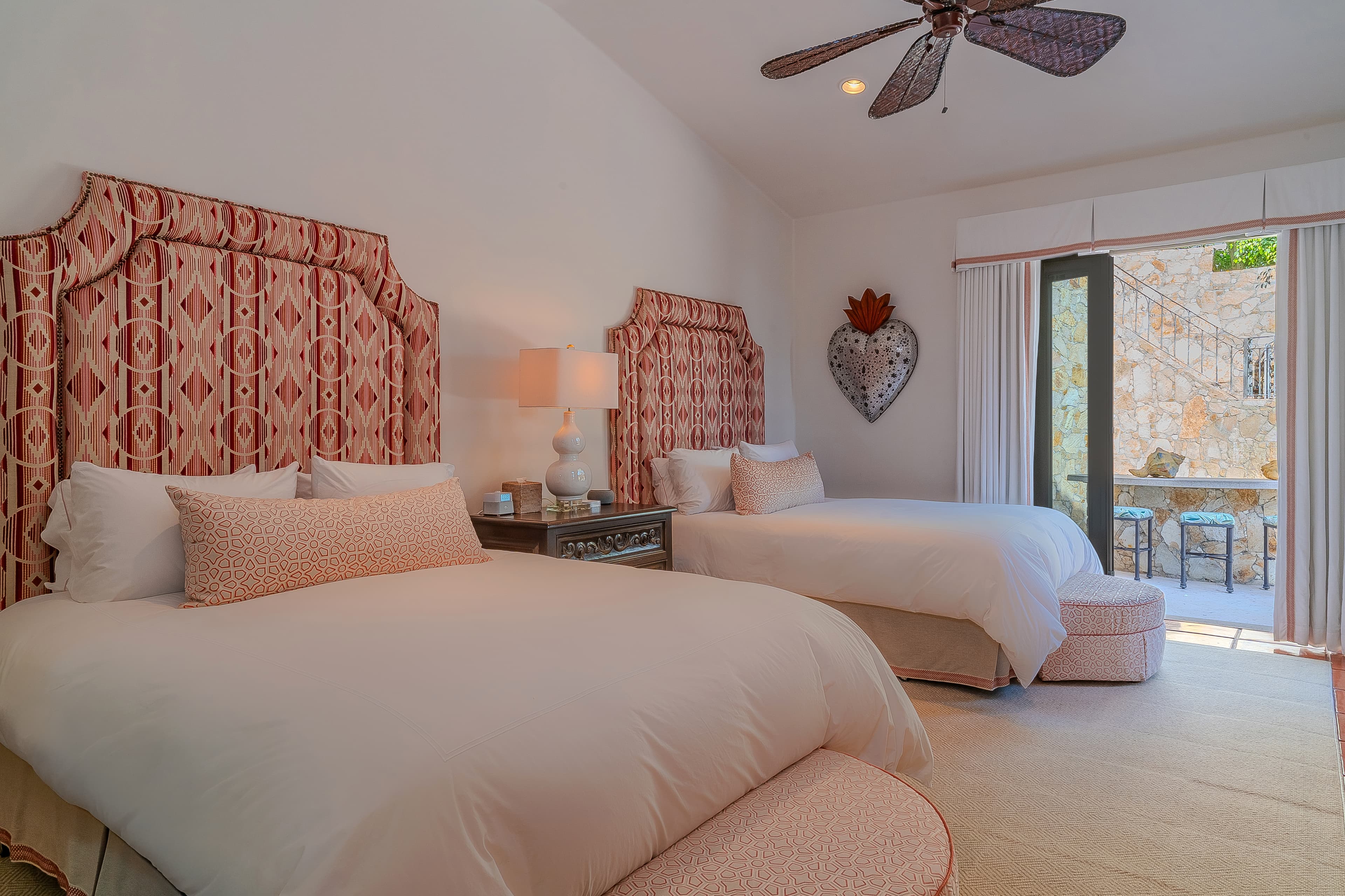 Bedroom 4 · Wake up in this charming bedroom where plush linens and designer touches meet your private balcony access. Soft coral accents and thoughtful lighting create your perfect retreat after a day of adventure.