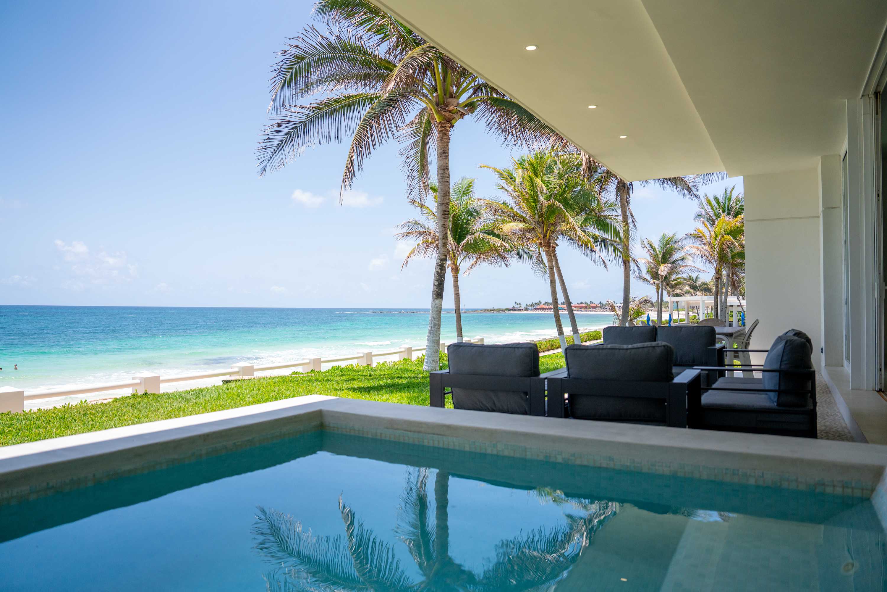 Luxury resort with a private plunge pool and ocean view with palm trees.