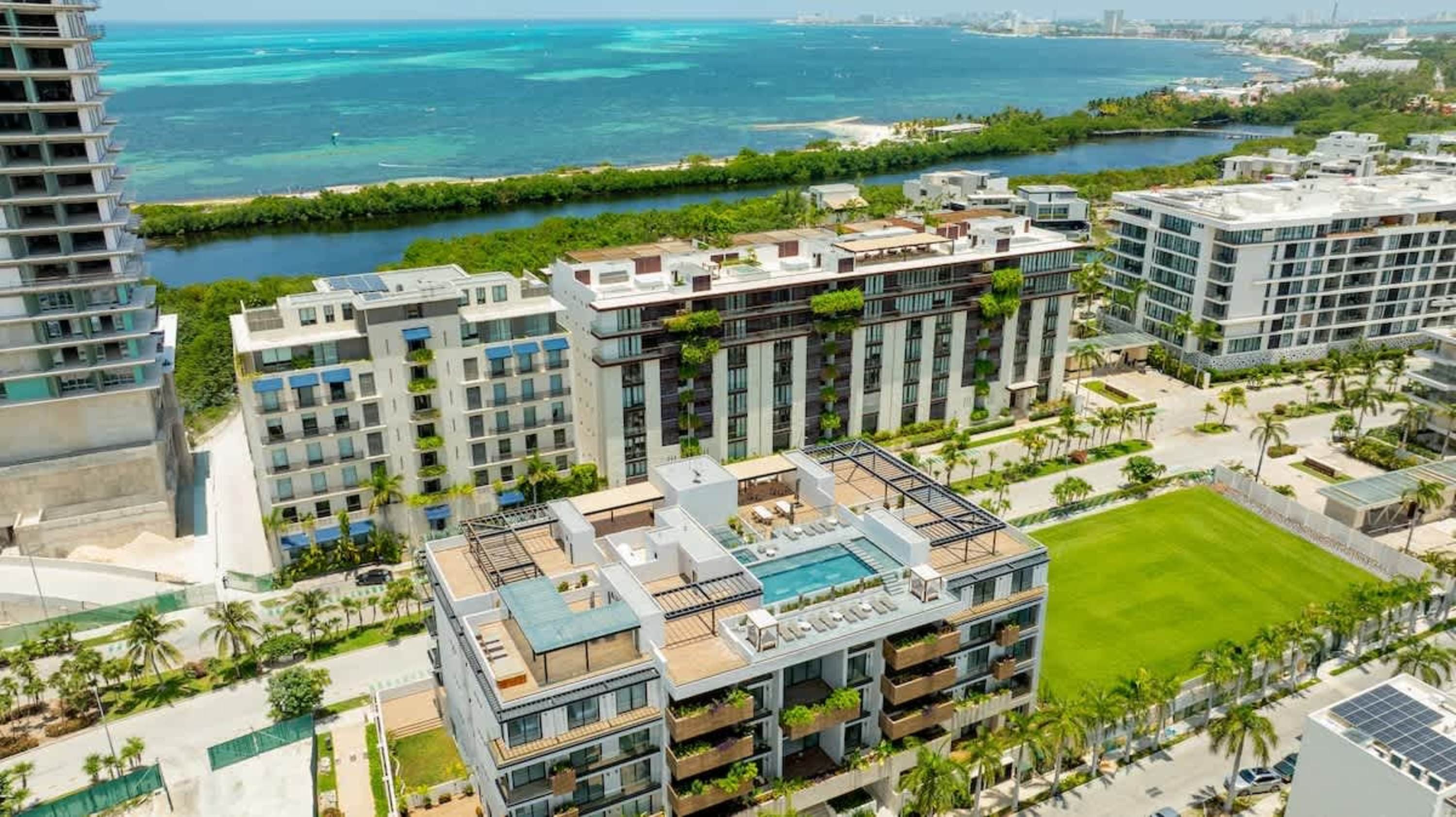 Modern buildings with pools and balconies, overlooking a bay.