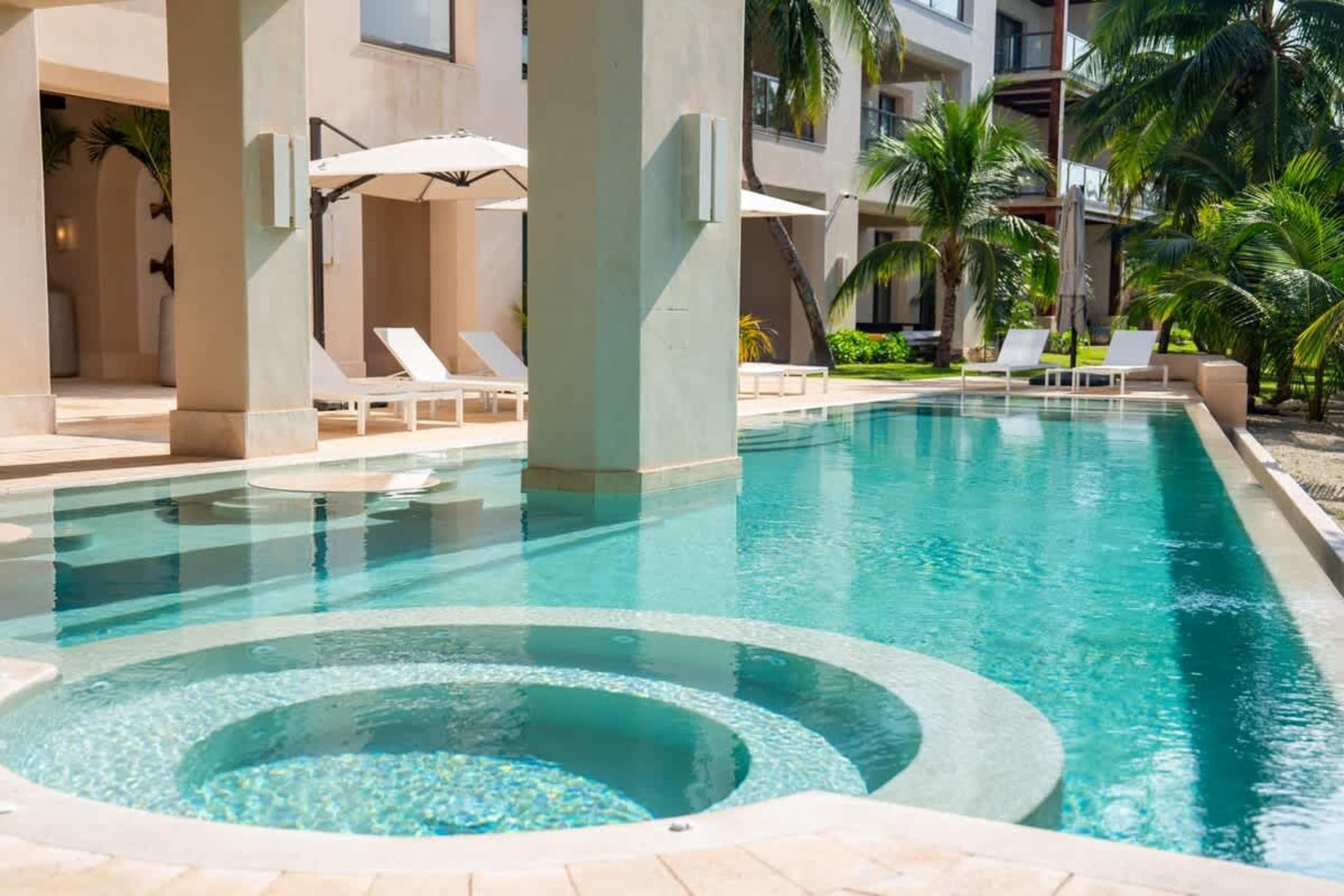 A resort pool with lounge chairs and palm trees.