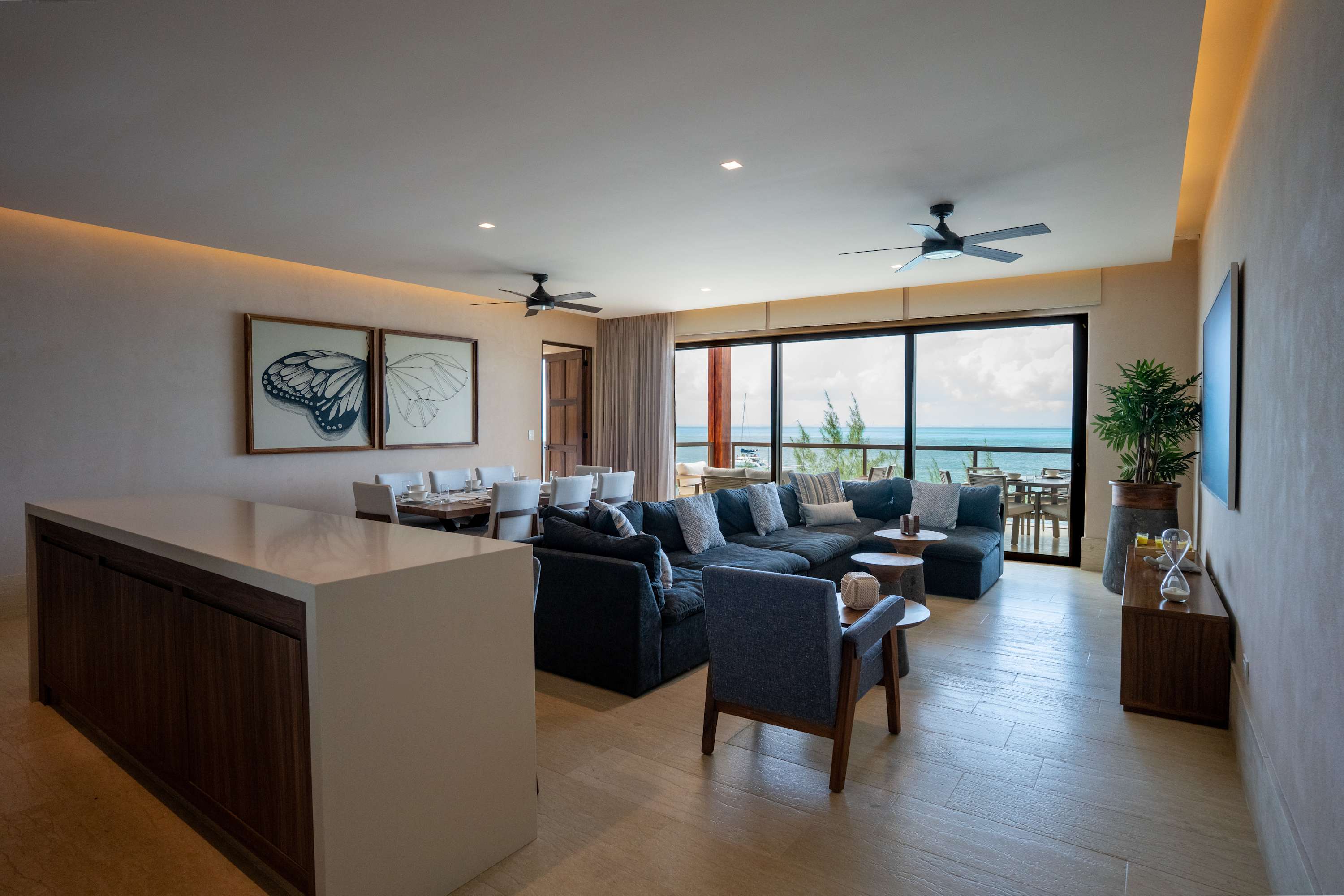 A modern living room with a sectional sofa, dining table, and ocean view.