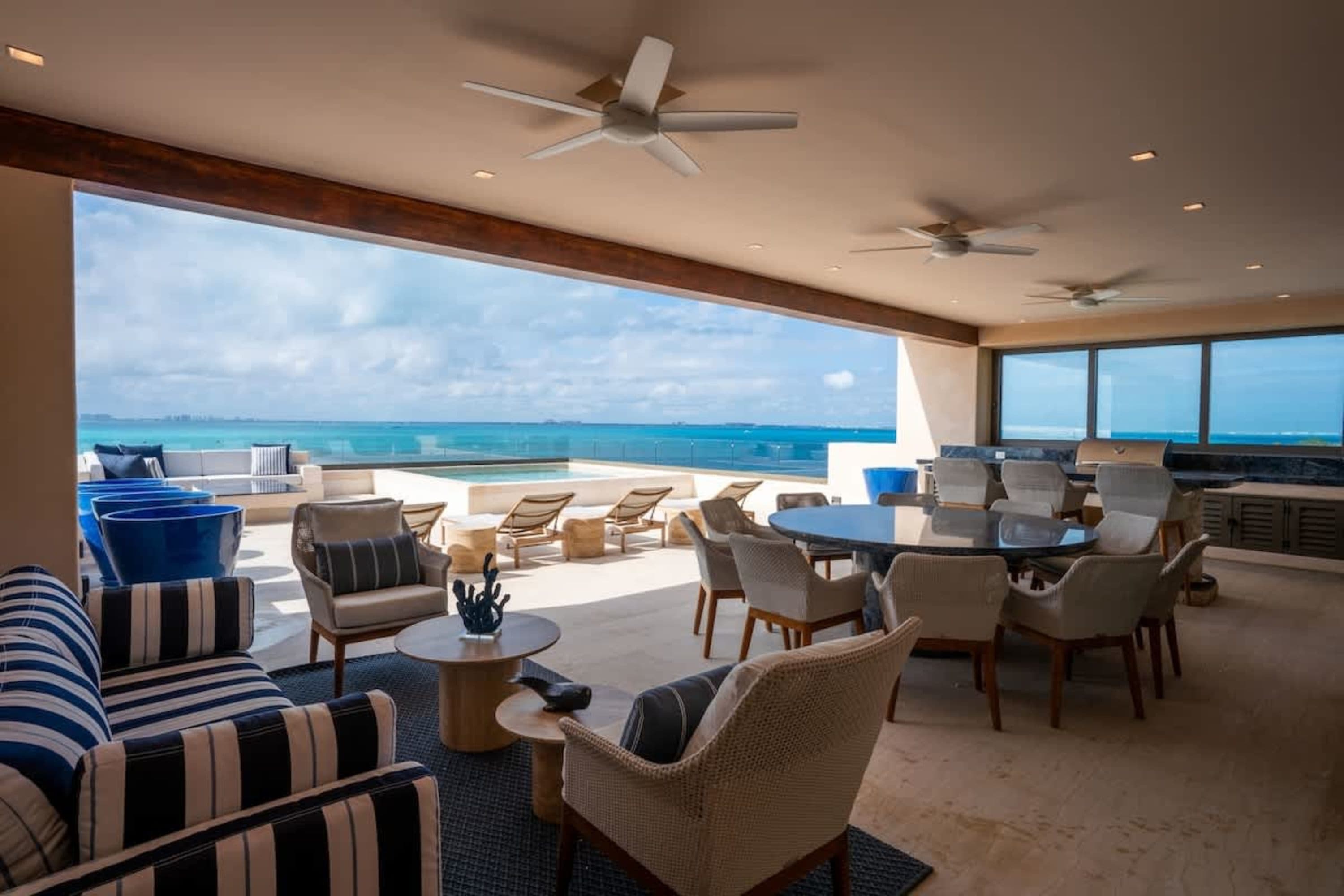 Luxury patio with ocean view, seating, dining table, and outdoor kitchen.